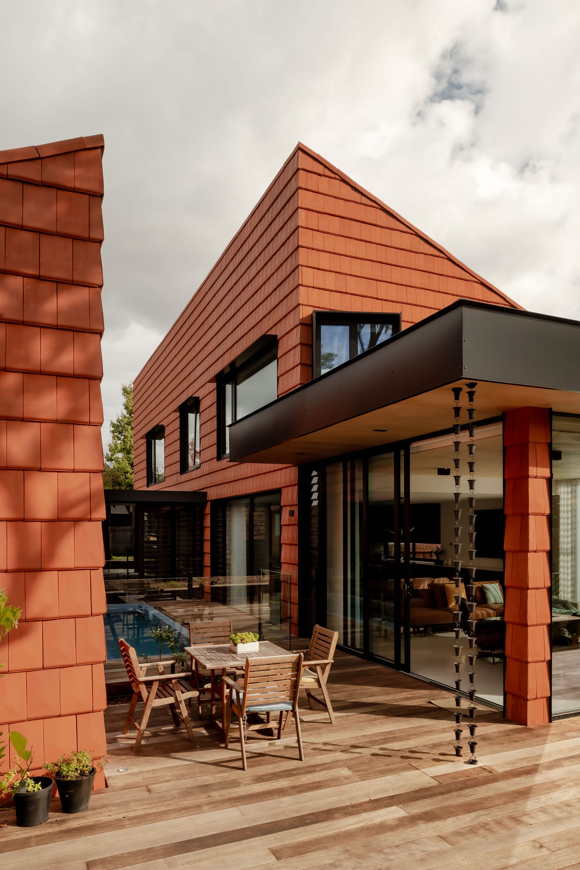 Mahogany House by R Architecture. House units featuring terracotta shingle facade facing patio with outside dining and pool.