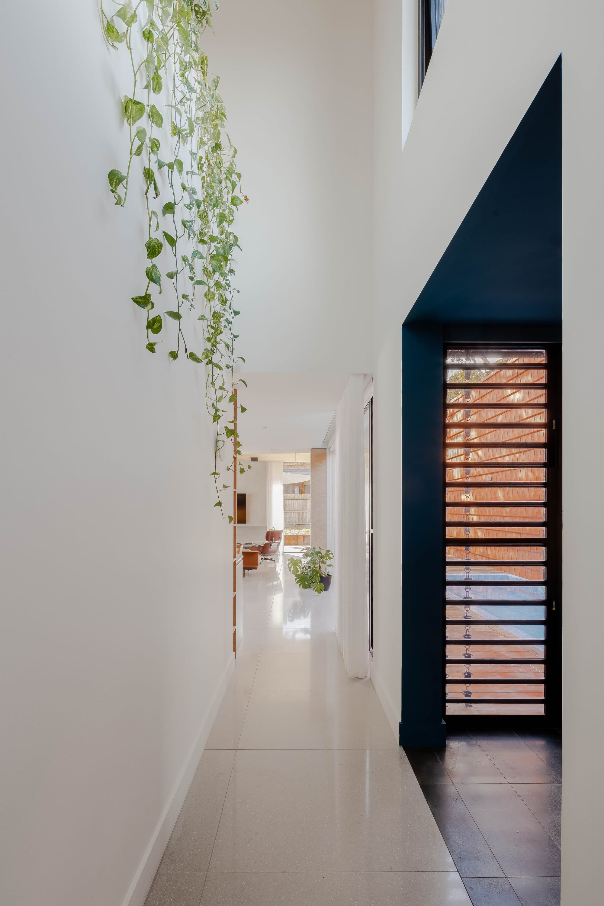 Mahogany House by R Architecture. Large white hallway with view to living room and open doors facing inner courtyard.