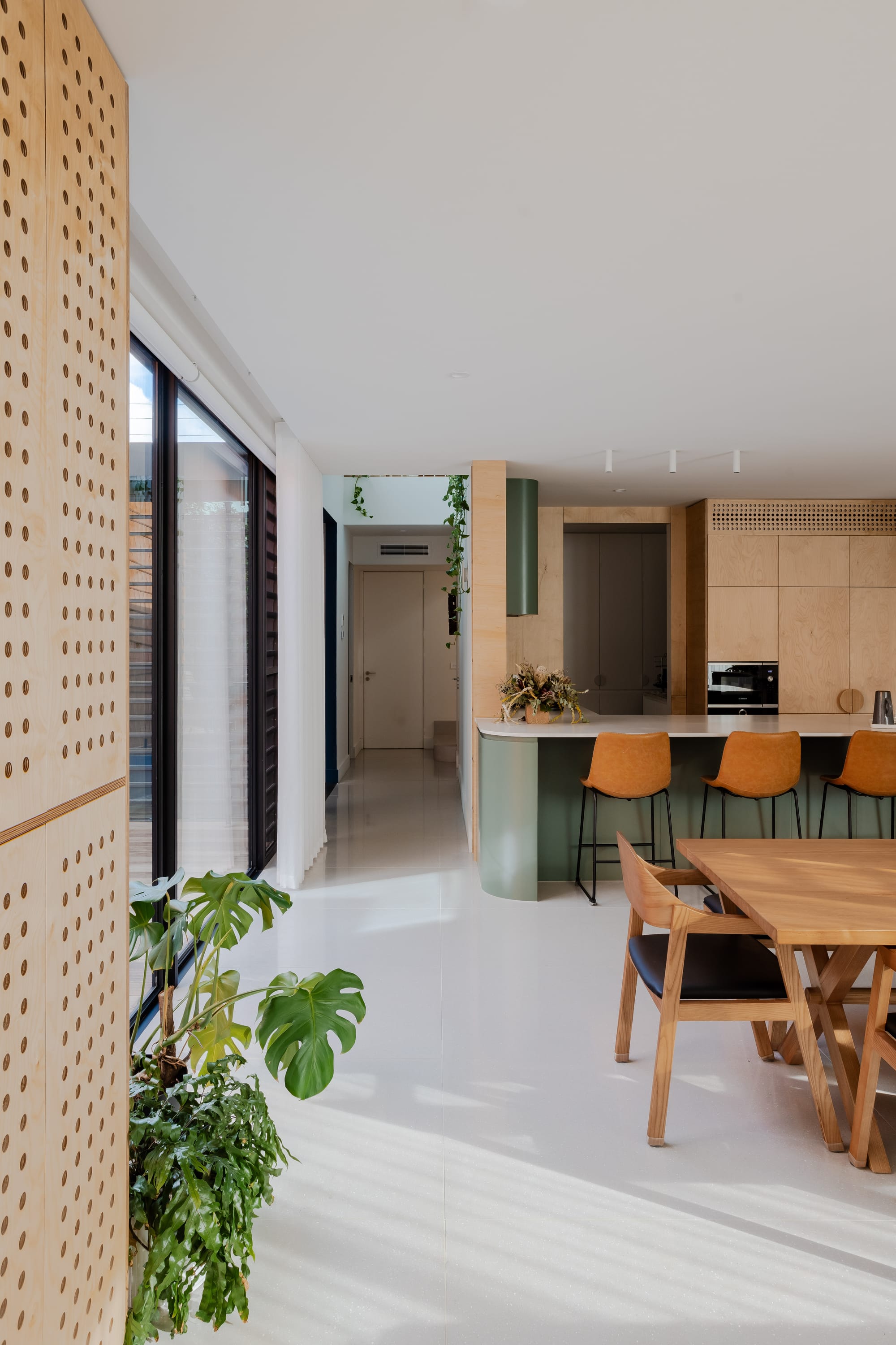 Mahogany House by R Architecture. Modern kitchen space interior featuring perforated plywood cupboard doors kitchen island and dining table.