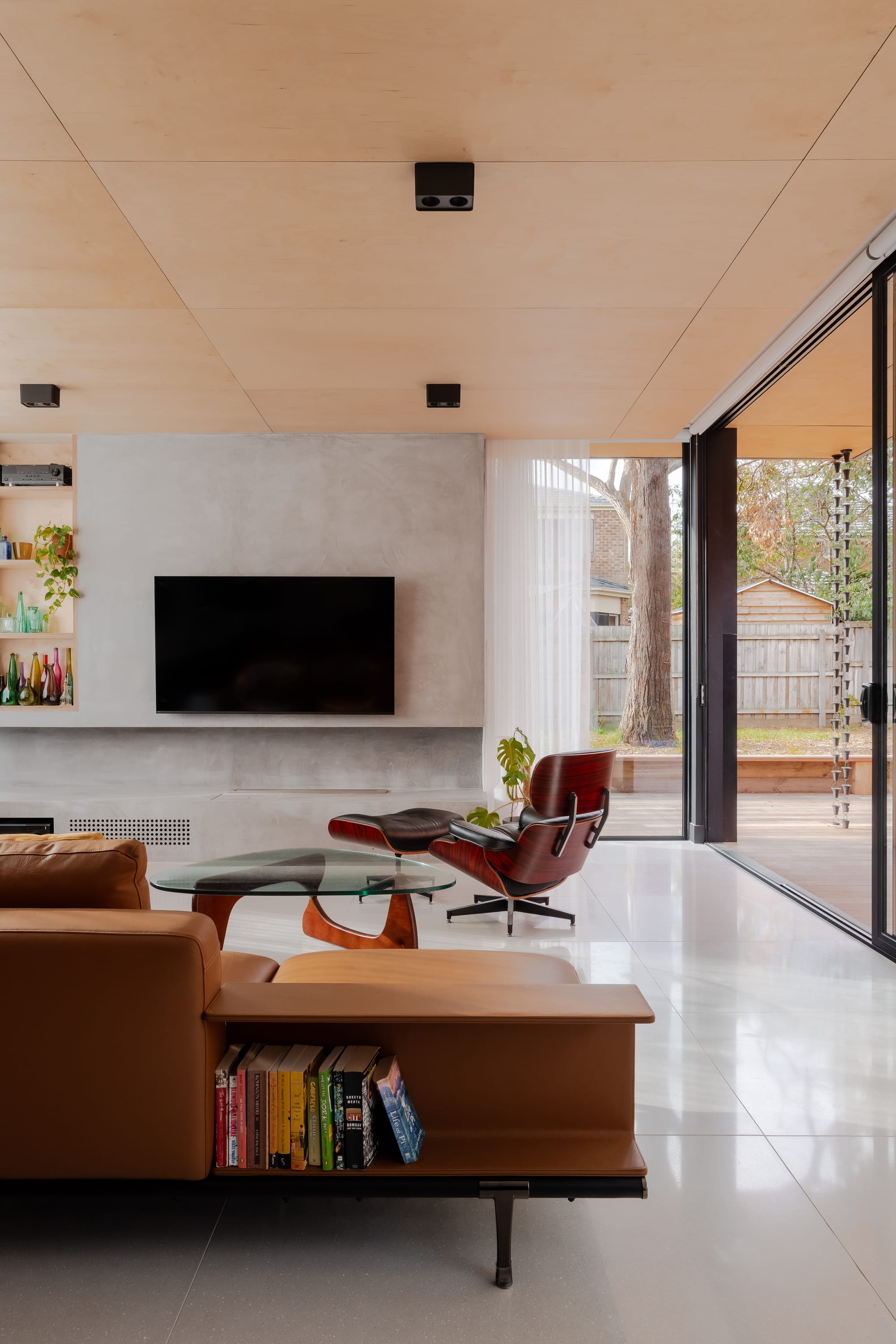 Mahogany House by R Architecture. Modern minimalistic living room featuring leather sofa, concrete walls and plywood ceiling.