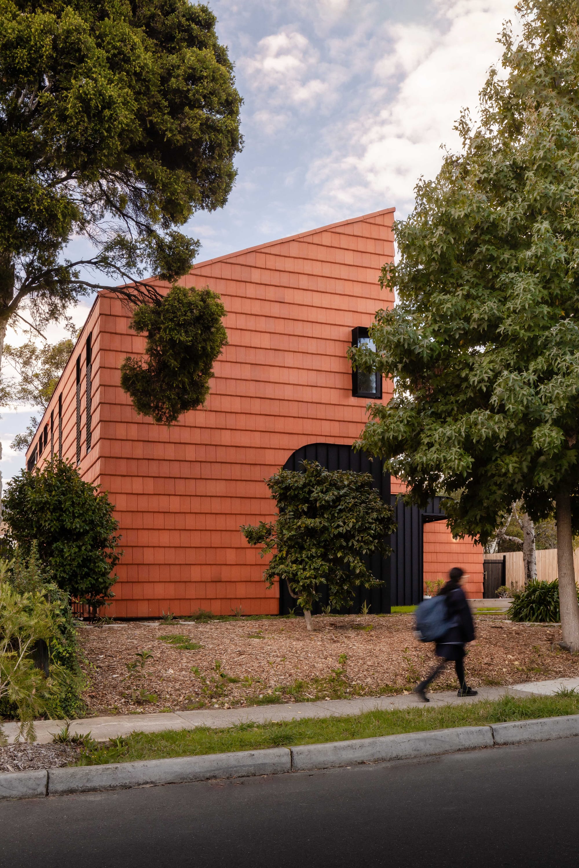 Mahogany House by R Architecture. Terracotta shingle facade featuring pitched roof.