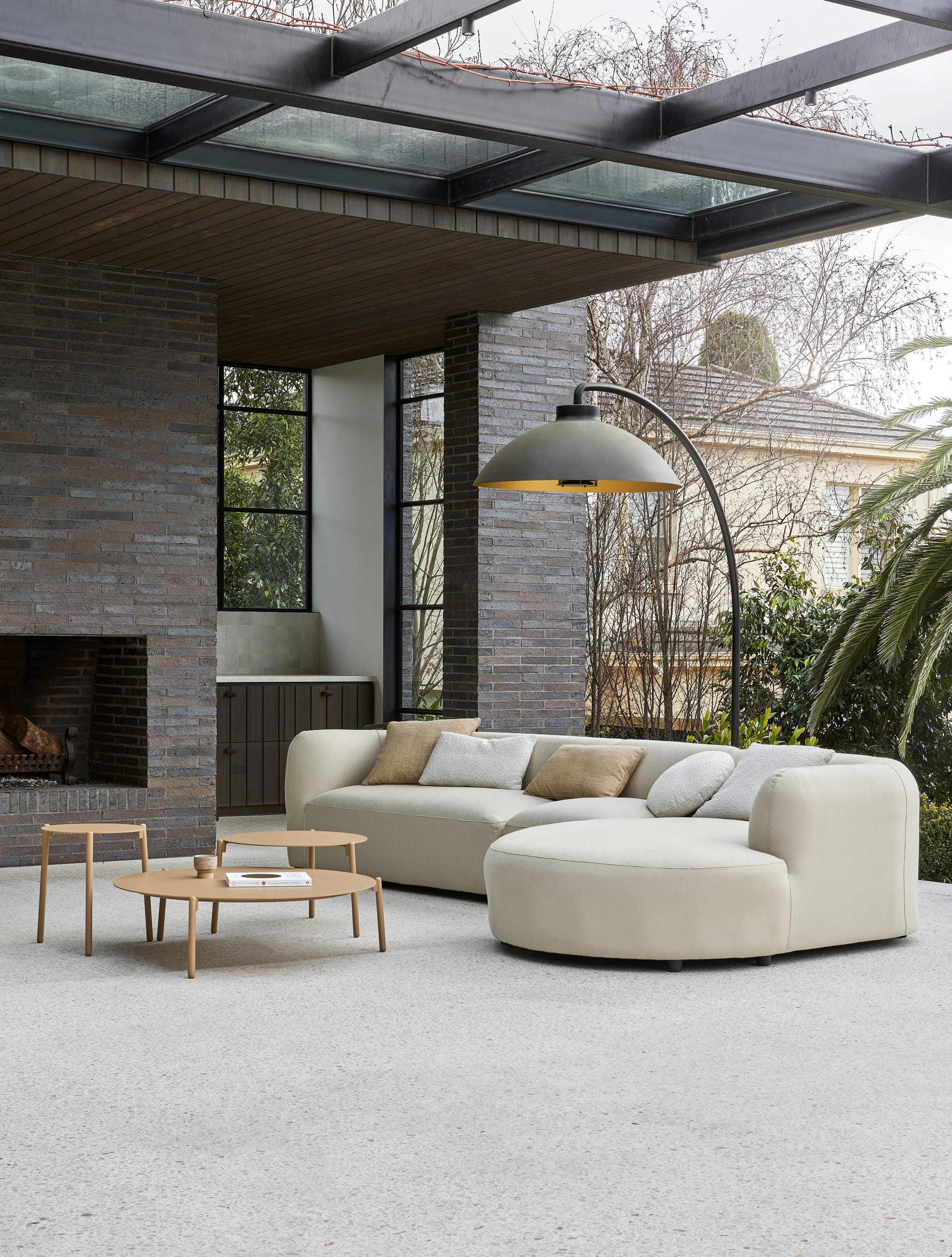 Melba Outdoor Sofa by GlobeWest. Loggia featuring chimney and sand coloured sofa with wooden coffee table set.