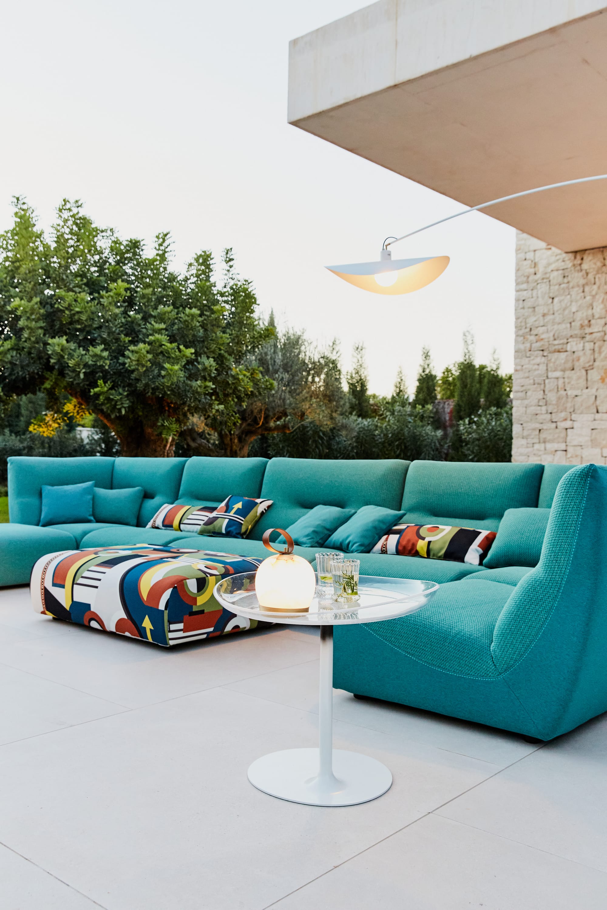 Outdoor Collection by Roche Bobois. Turquoise outdoor sofa next to modern house.