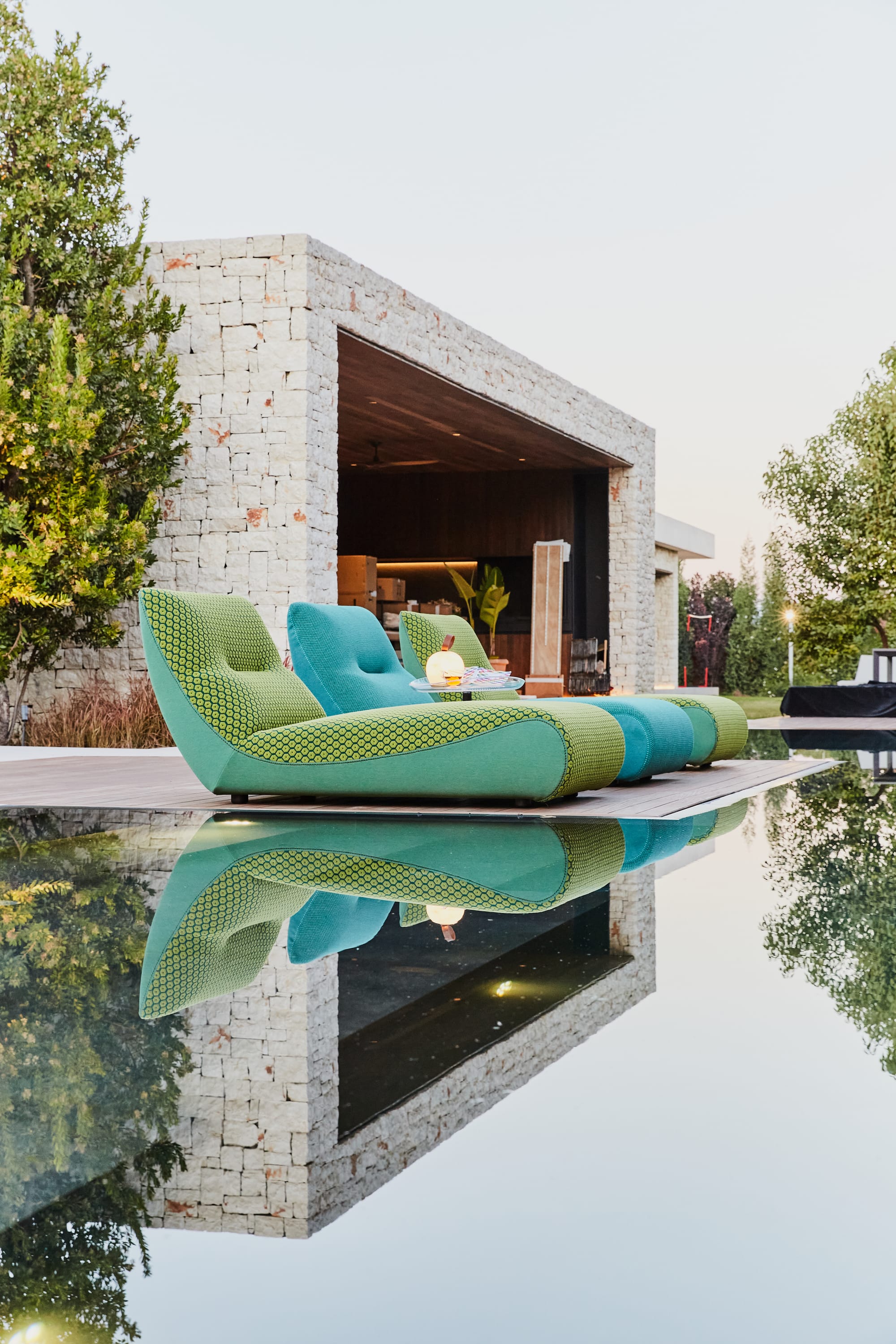 Outdoor Collection by Roche Bobois. Turquoise outdoor foam sun beds next to modern house and pool.