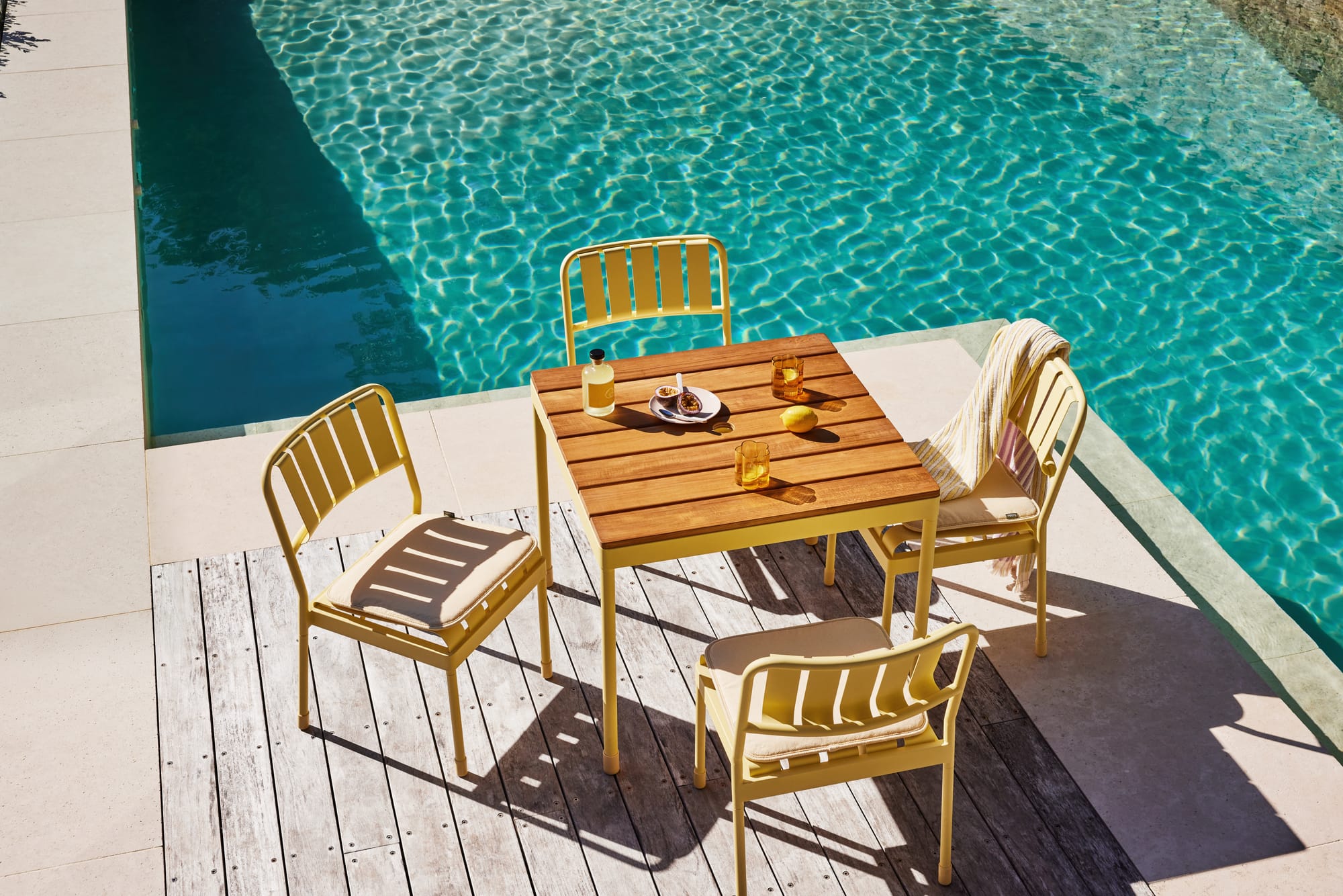 Torakina Outdoor by Koala Living. Model at pool on outdoor dining set featuring soft yellow dining chair and dining table.