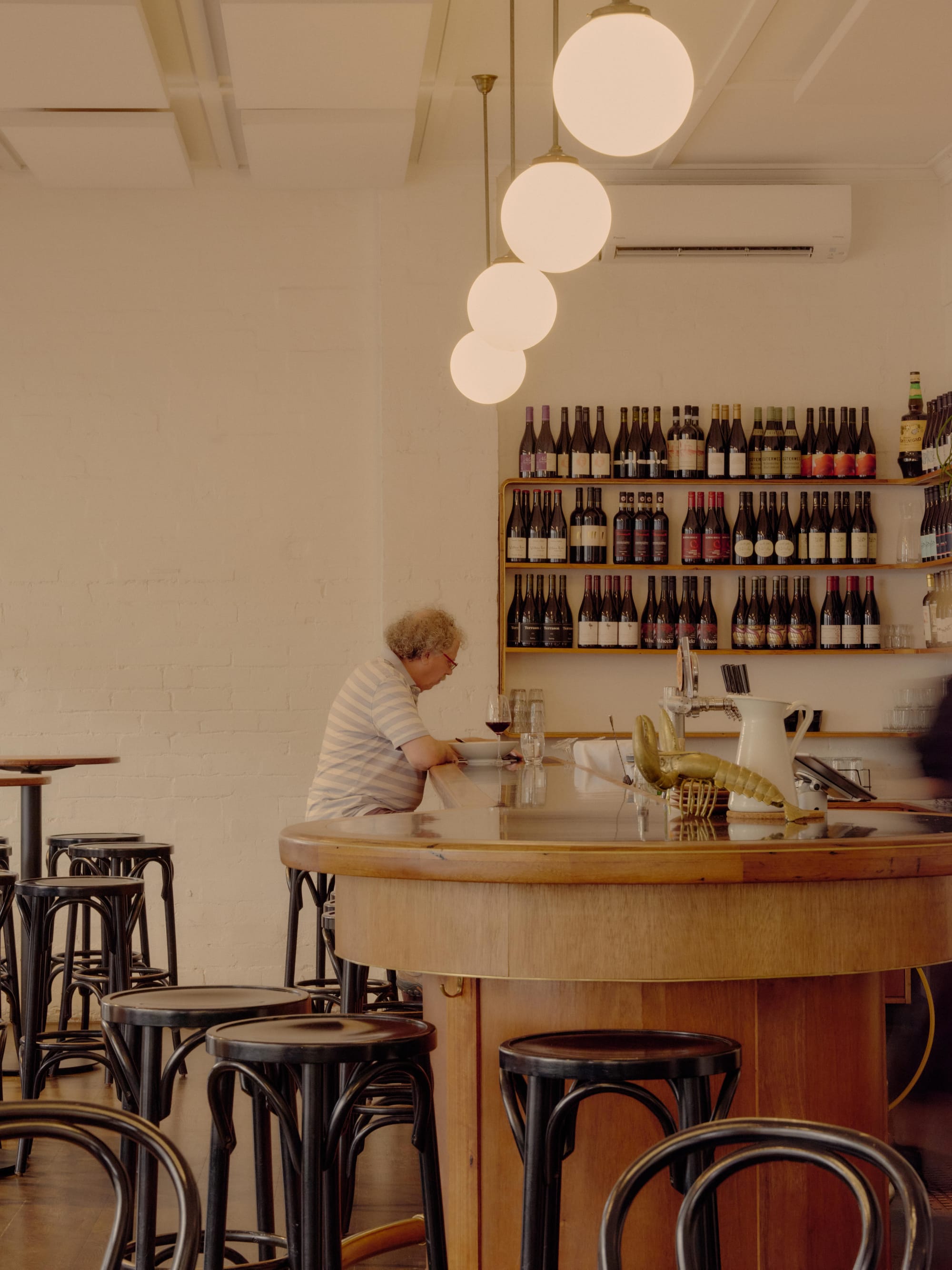 An interior shot of a Clifton Hill bar with a man sitting at the bar having wine and food.