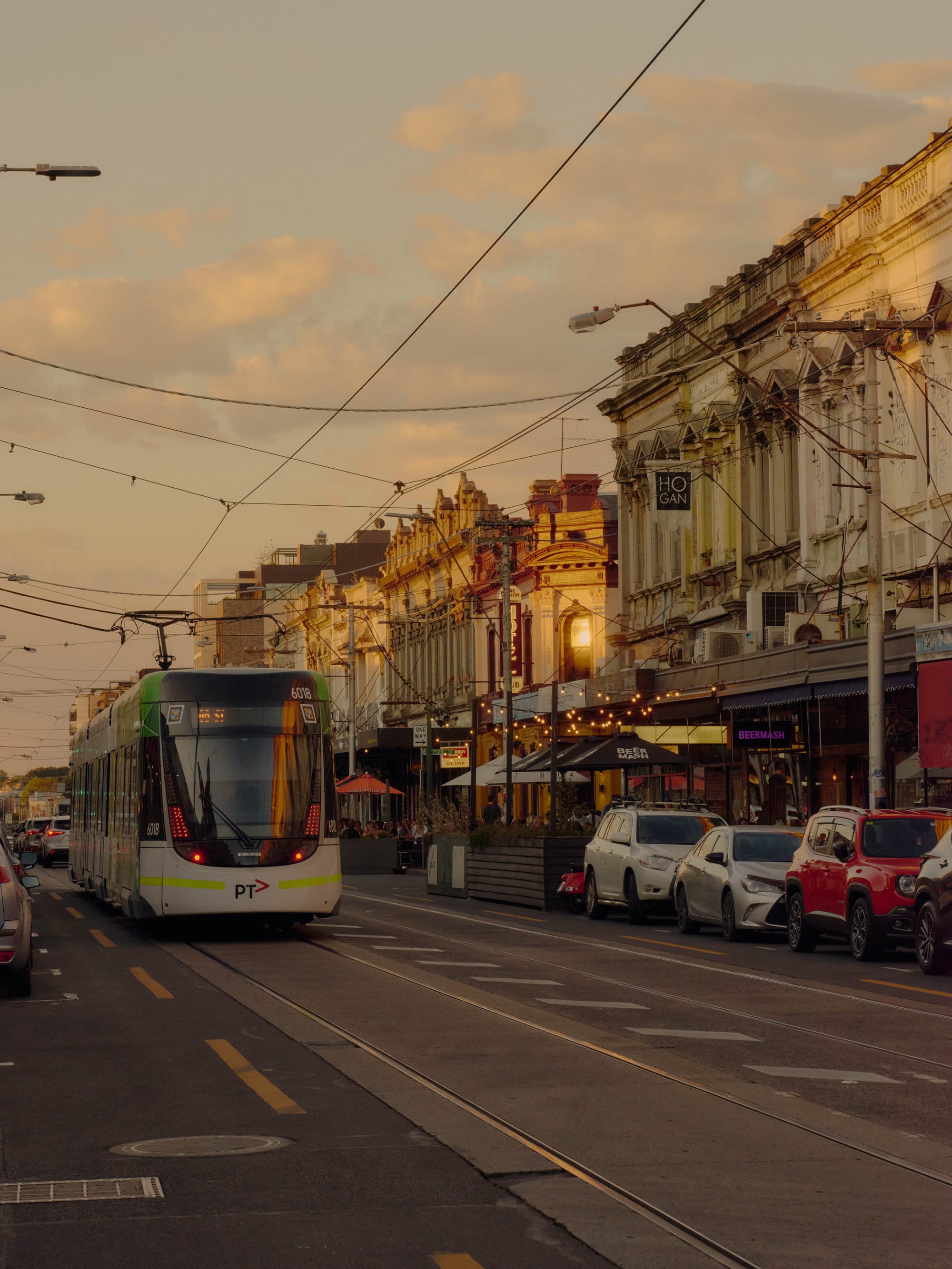 A shot of a Clifton Hill street showing the heritage shopfronts and a tram along the road.