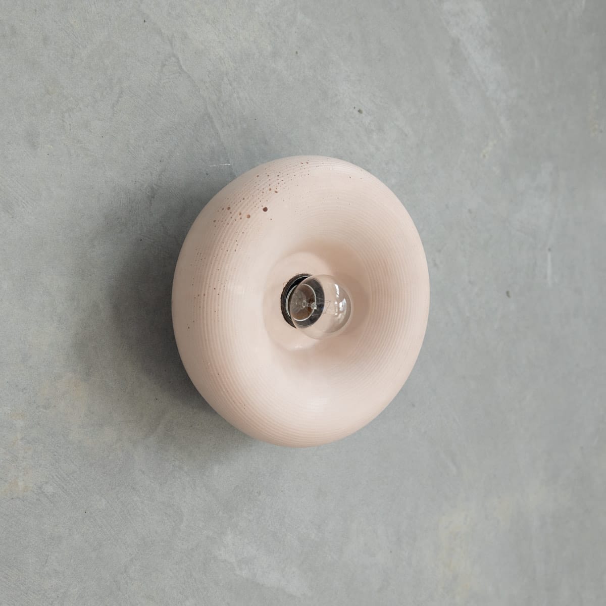 Haze Wall Sconce in Nude. Image copyright of Crete Studio. Nude pillowey concrete wall sconce on grey concrete wall.