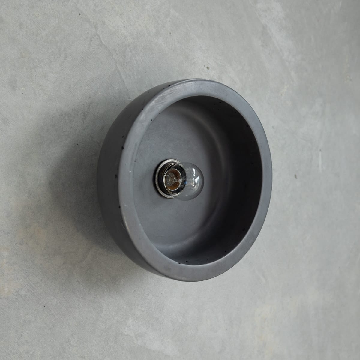 Small Hakea Sconce in Charcoal. Image copyright of Crete Studio.  Dark grey bowl lighting wall fixture on concrete wall. 