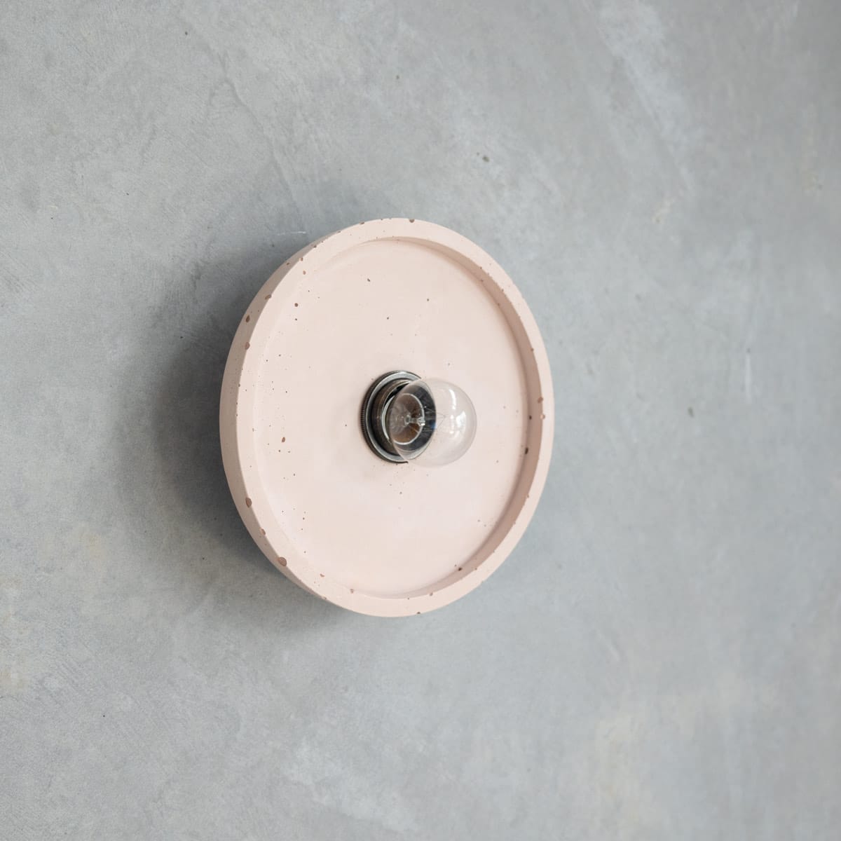 Loman Wall Light in Nude. Image copyright of Crete Studio. Light baby pink flat wall fixture on concrete wall. 