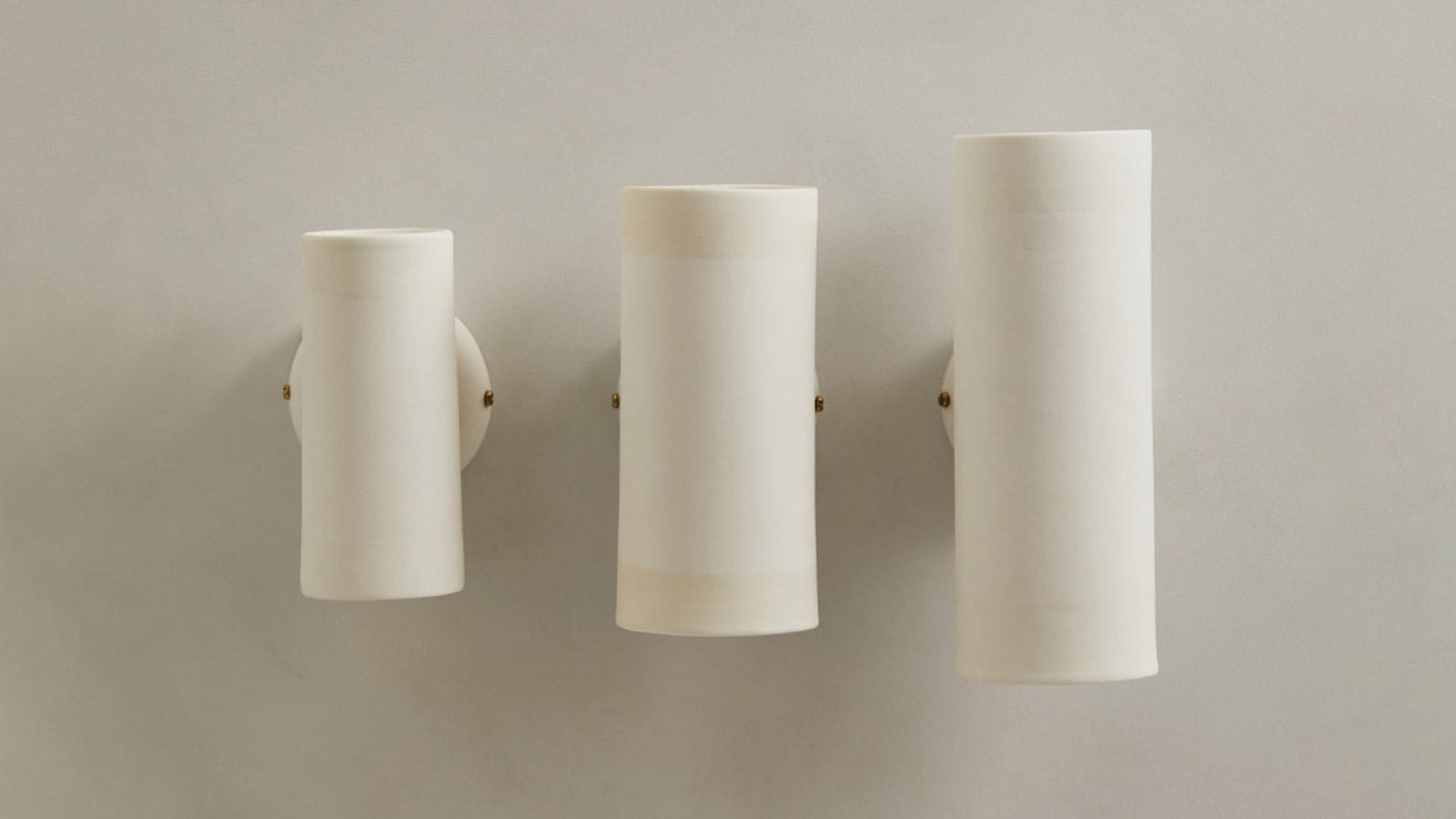 Dusked Eos Wall Light by Studio Etni with Lighterior. Three tube shaped white wall lights in different sizes.