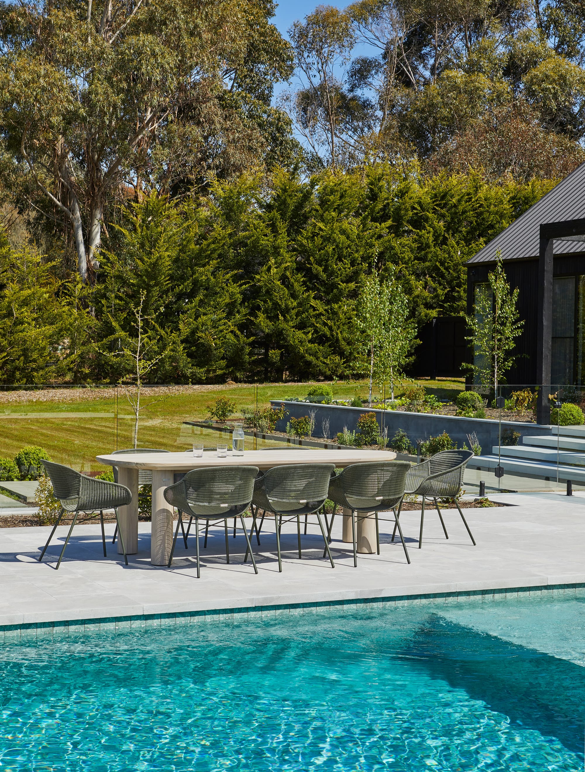 Seb Outdoor Dining Table & Cabana Curve Dining Chairs by GlobeWest. Dining table featuring green rattan outdoor chairs at pool in garden.