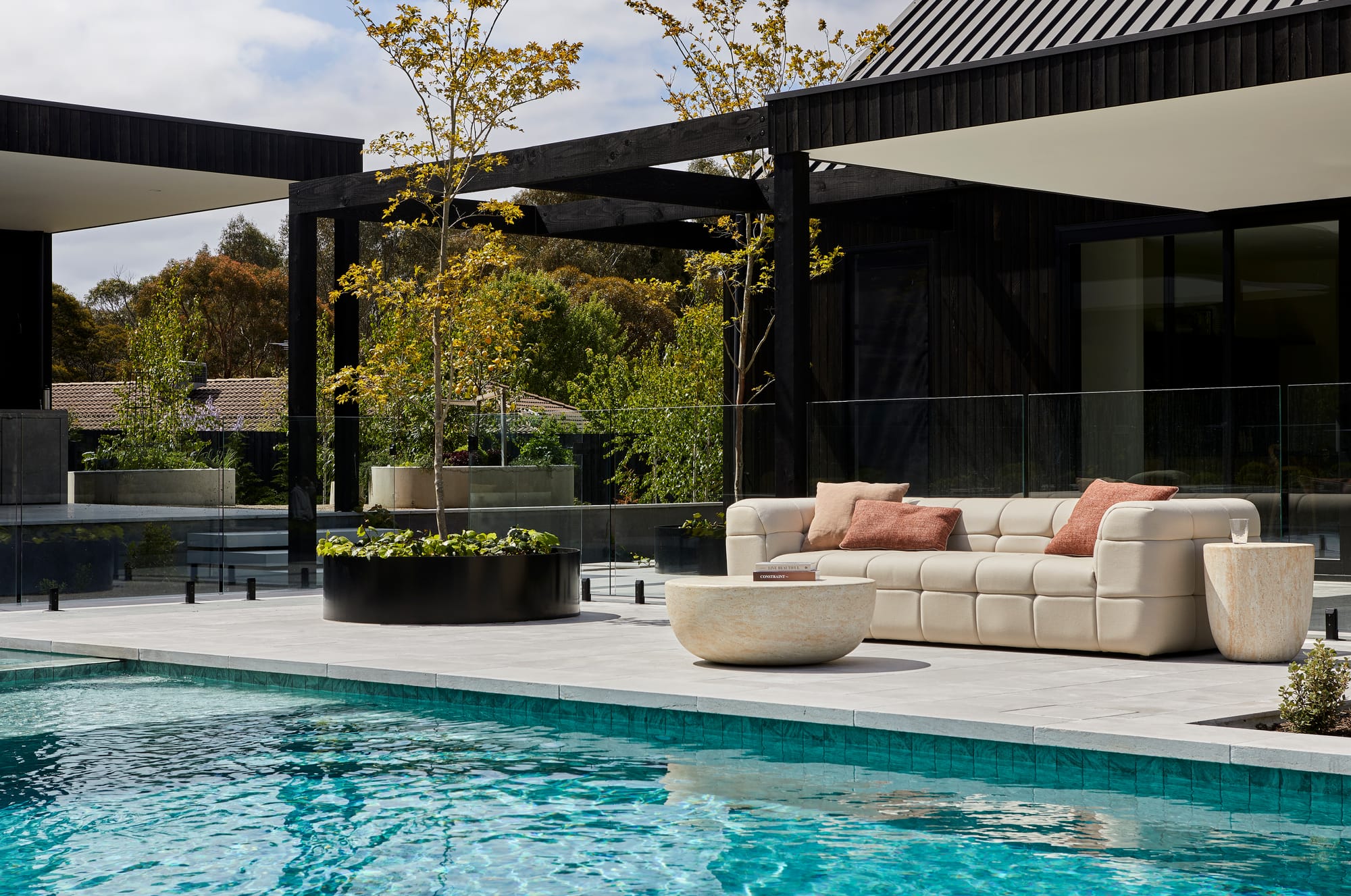 Vittoria Olive Outdoor Sofa by GlobeWest. Comfortable contemporary lounge sofa in sand tones and beige marble coffee table at pool in front of modern house.