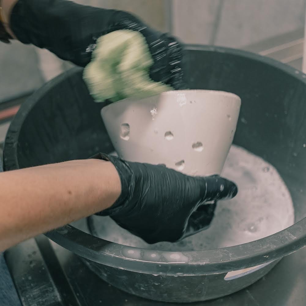 Crete Studio. Image copyright of Crete Studio. Hands cleaning raw concrete pendant light fixture in a bucket. 