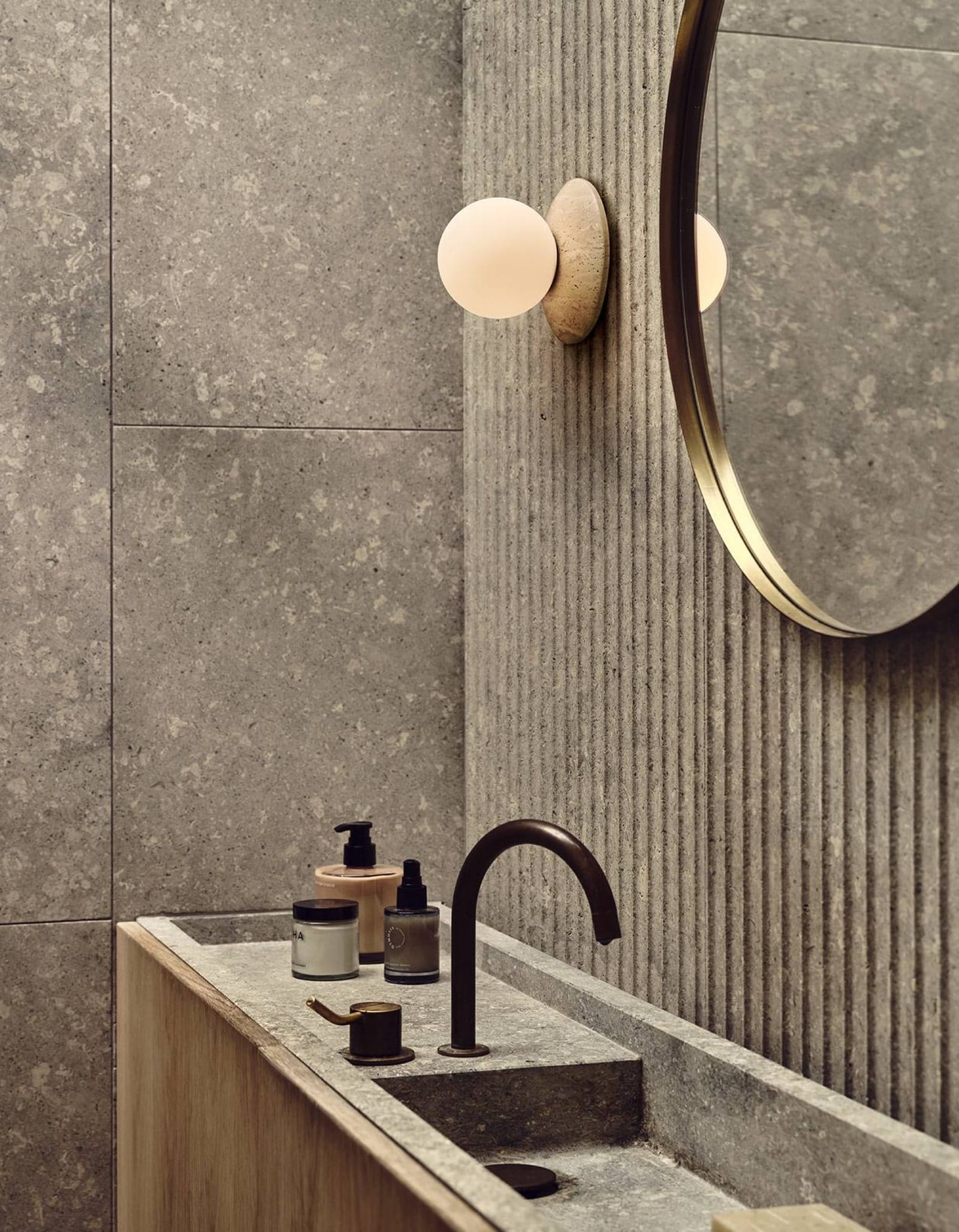 Orbit Wall Light by J. Adams & Co. with Lighterior. Bathroom interior featuring round wall light, round mirror and concrete tiles.