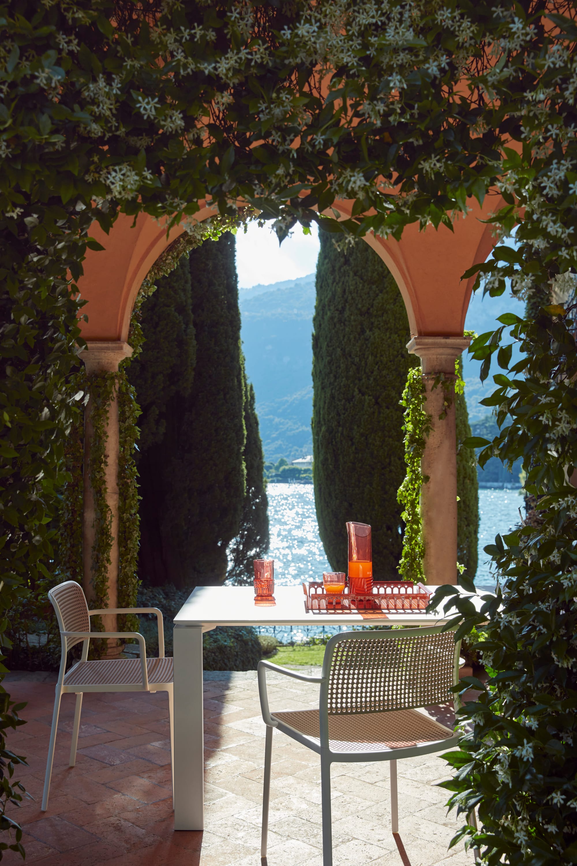 Outdoor Collection Audrey Chair by KartellPerth. Modern dining setting with arched view to Mediterranean  lake and landscape.