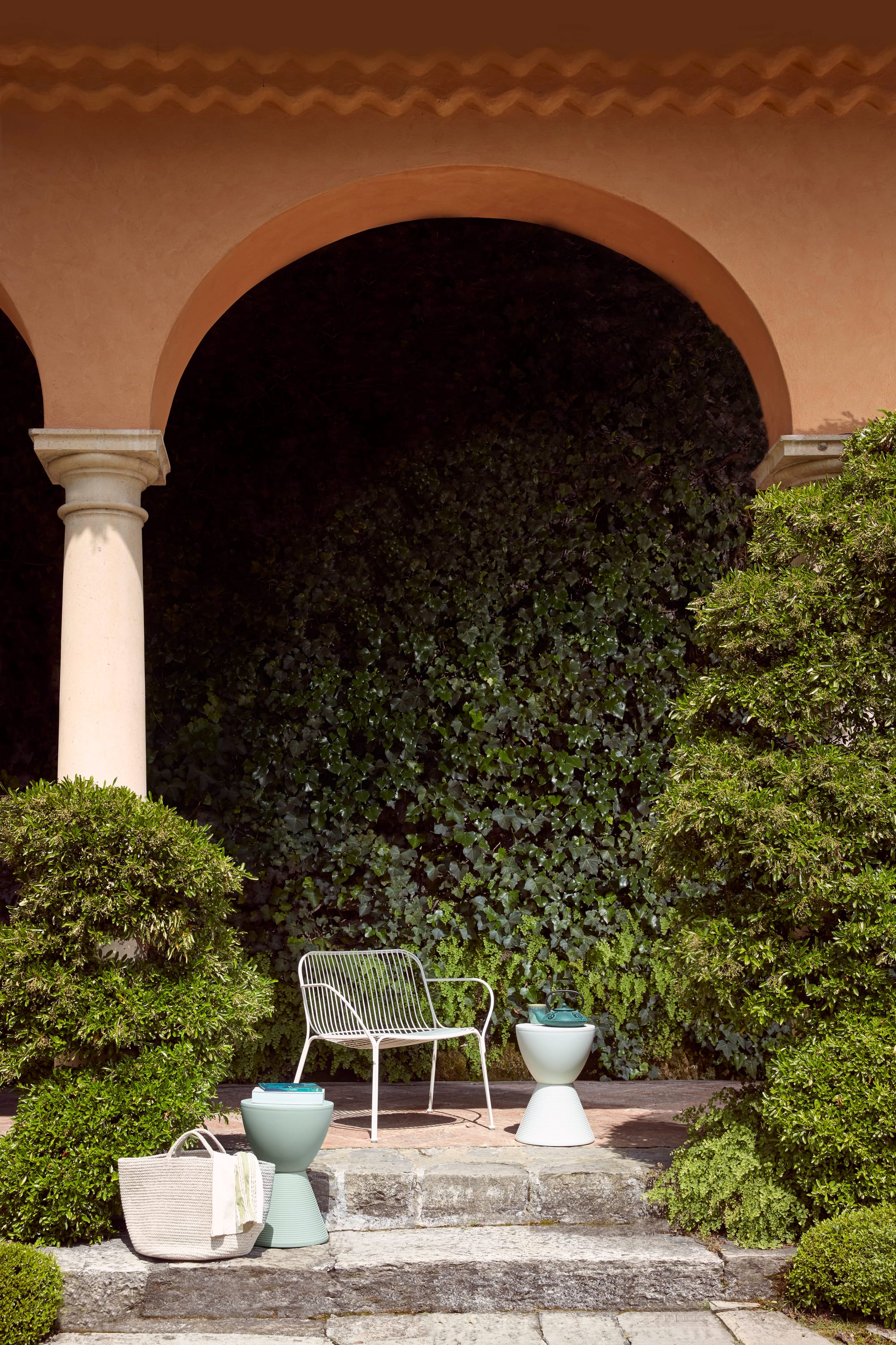 Outdoor Collection Hiray Arm Chair by KartellPerth. Modern white powder coated steel armchair below arch in garden.