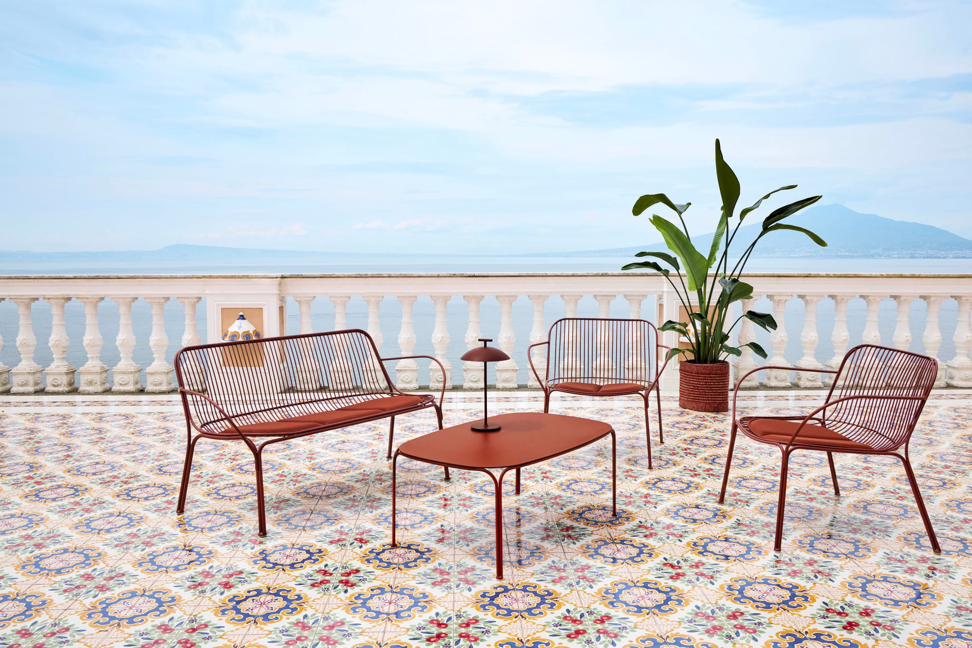 Outdoor Collection Hiray by KartellPerth. Steel frame brick powder coated outdoor lounge set on Mediterranean balcony featuring colorful tiles and view to ocean.