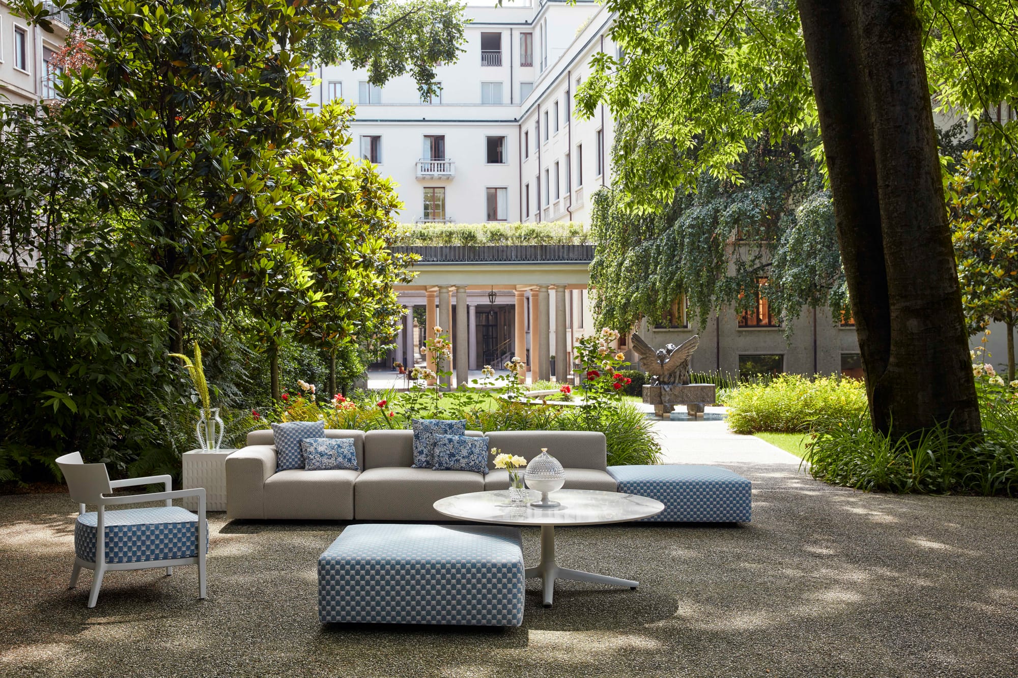 Outdoor Collection Cara Outdoor Armchair by KartellPerth. Inner green courtyard with outdoor lounge set including armchair, sofa and round coffee table.