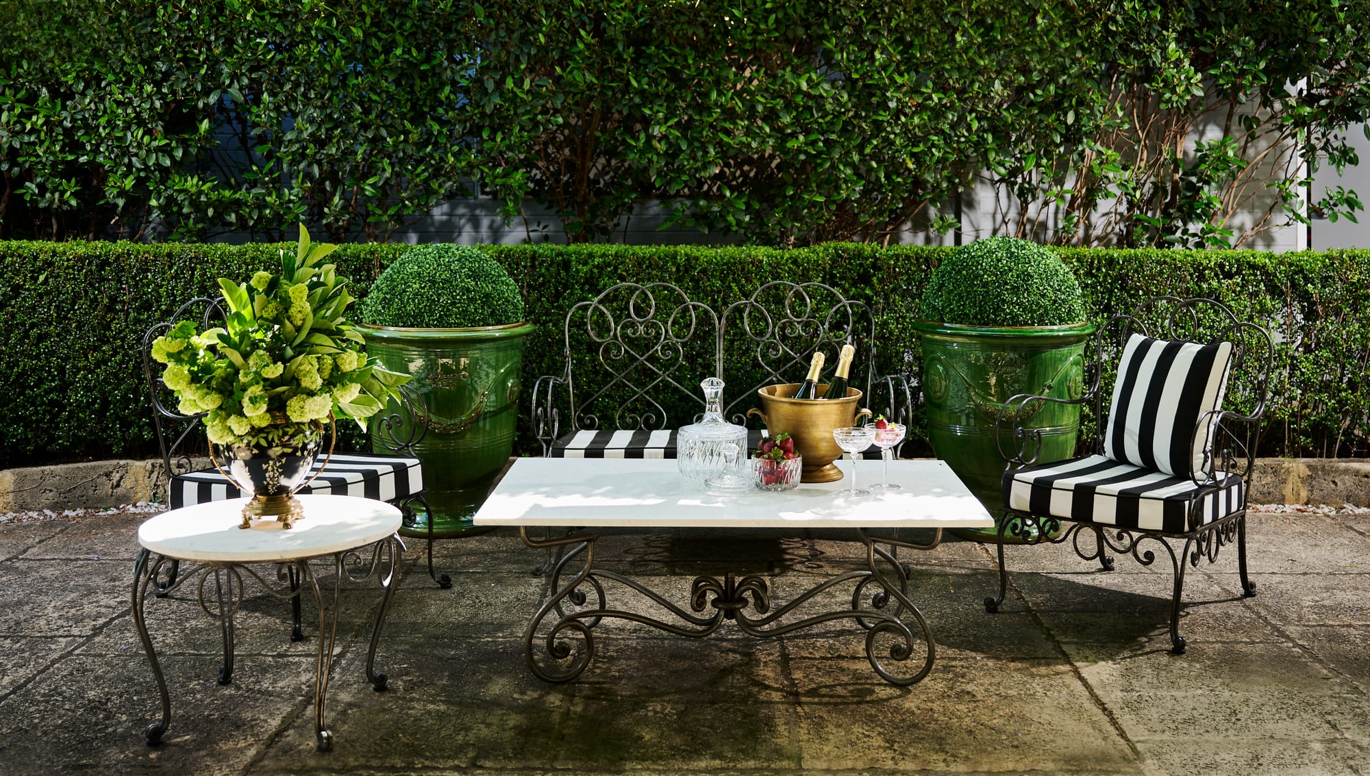 Le Forge Collection Arm Chairs, Coffee Tables and Authentic Anduze Collection Plant Pots by Trilogy. Metal Art de Nouveau outdoor lounge set featuring armchairs, round and squared coffee tables.