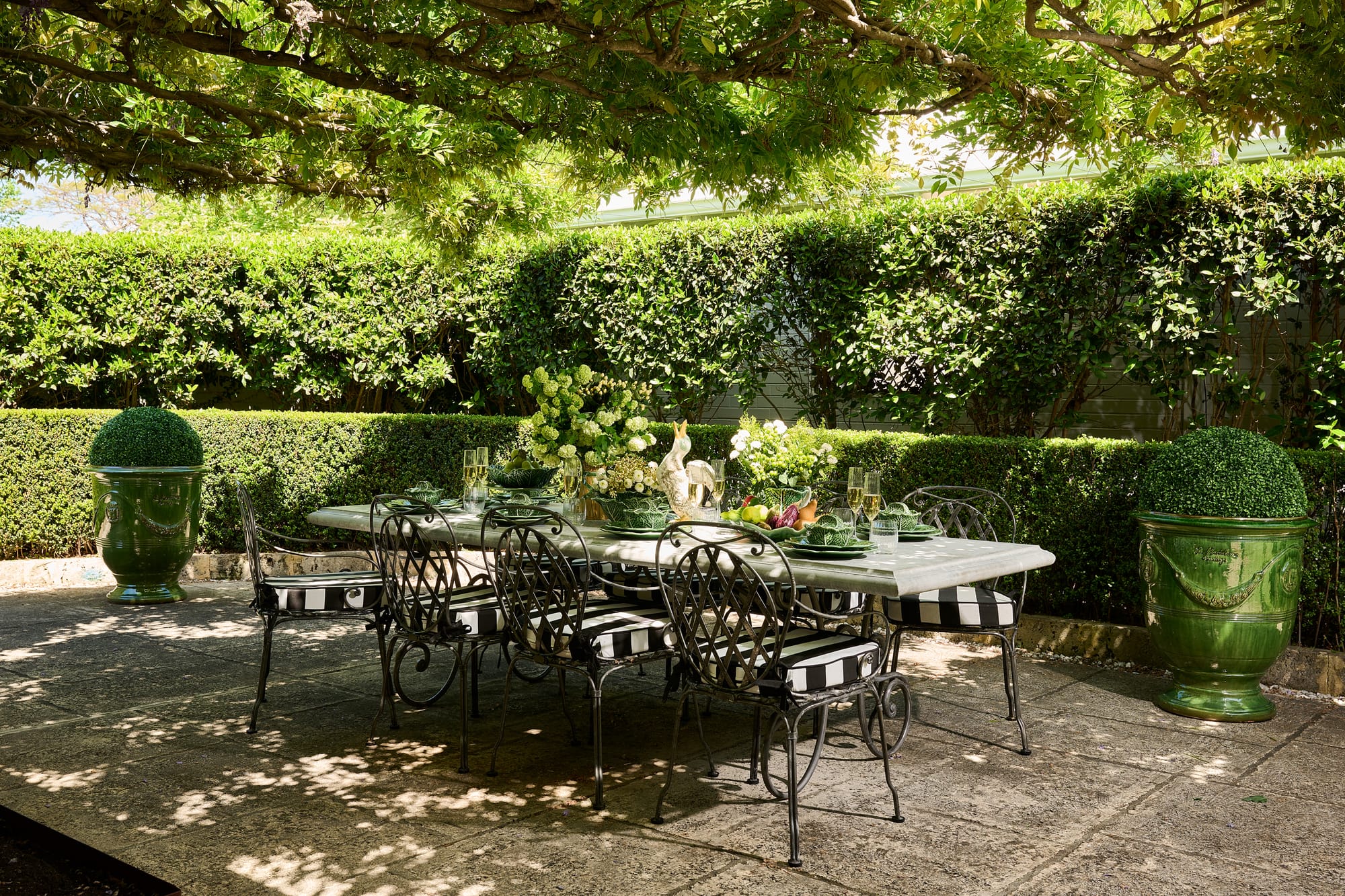 Le Forge Collection Dining Set and Authentic Anduze Collection Plant Pots by Trilogy. Metal Art de Nouveau outdoor dining set and big green glazed plant pots on vegetated terrace.