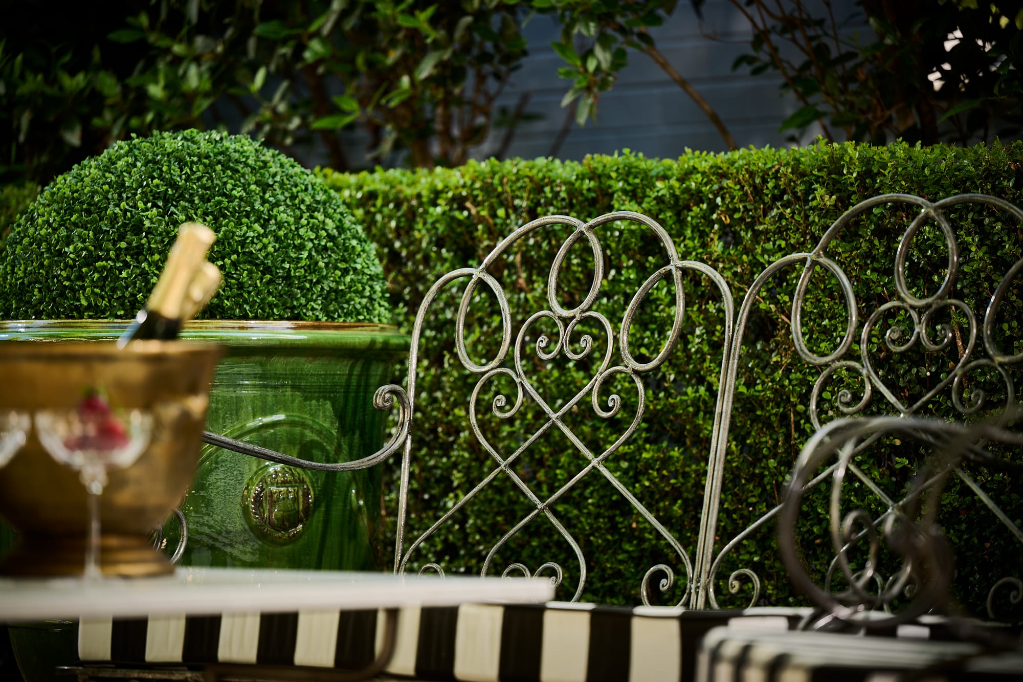 Le Forge Collection Chantilly Resort Chairs and Authentic Aduze Collection Plant Pots by Trilogy. Metal Art de Nouveau  dining chair detail and Champagne on summer terrace.