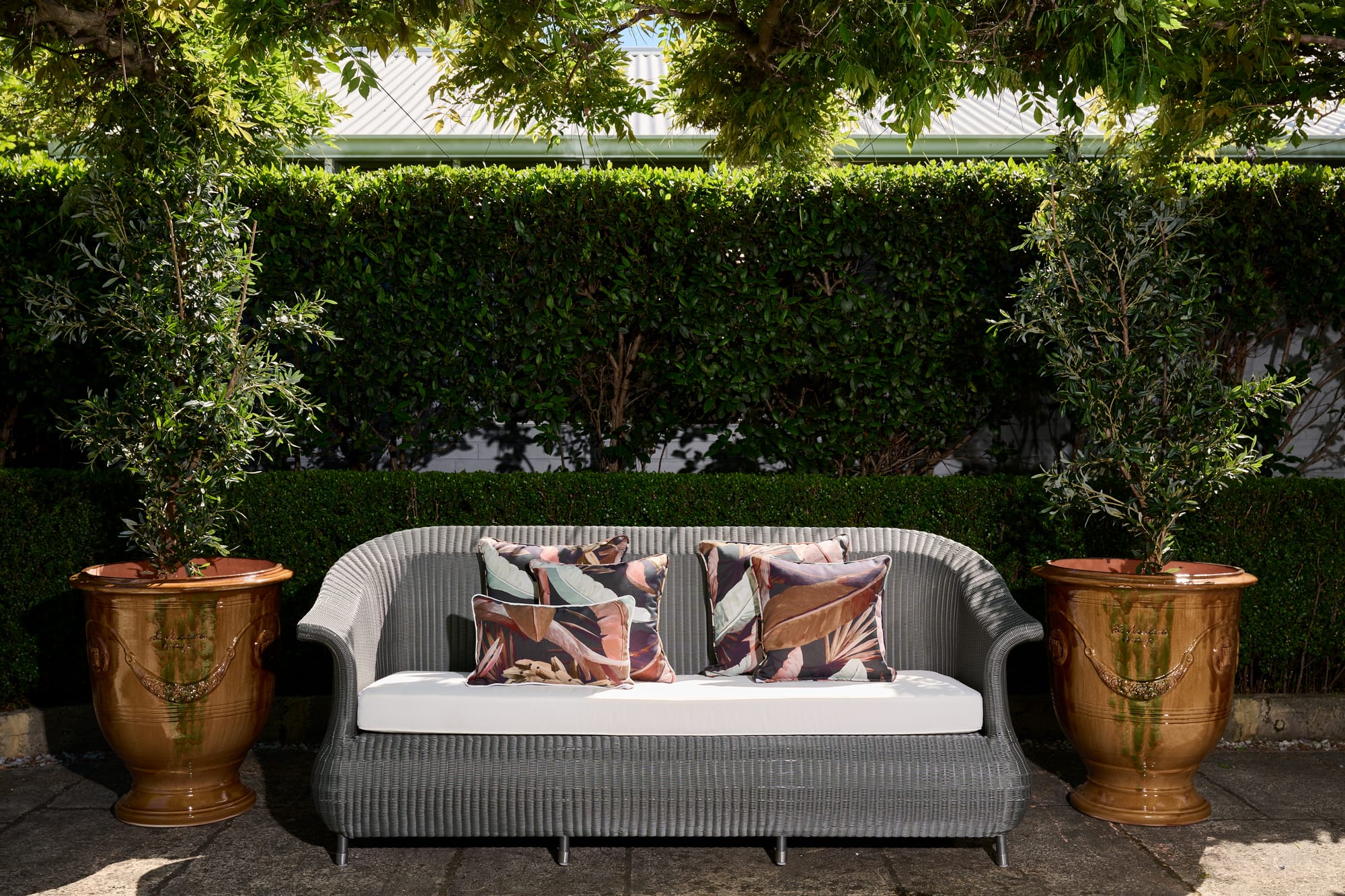 Syntetic Loom Collection Davenport 2 Seater and Authentic Aduze Plant Pots by Trilogy. Modern plaited outdoor 2 seater sofa and big brown glazed clay plant pots.