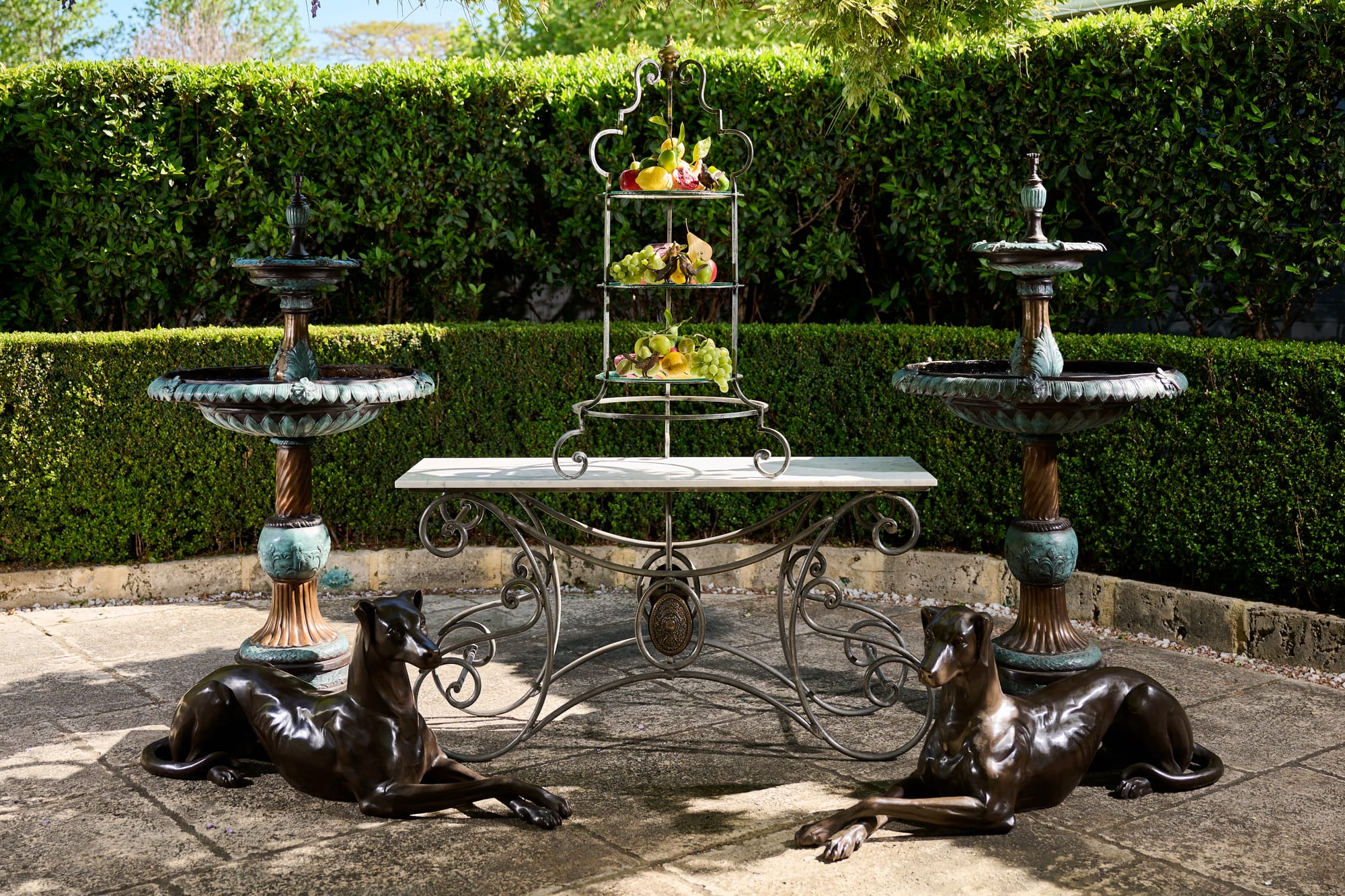 Le Forge Collection French Console Table and Patisserie Stand by Trilogy. Le Forge Collection St Tropez Sun Lounger and Authentic Aduze Collection Plant Pots by Trilogy. Metal Art Nouveau dining table, etagere, fountains and doberman ceramic sculptures on terrace.