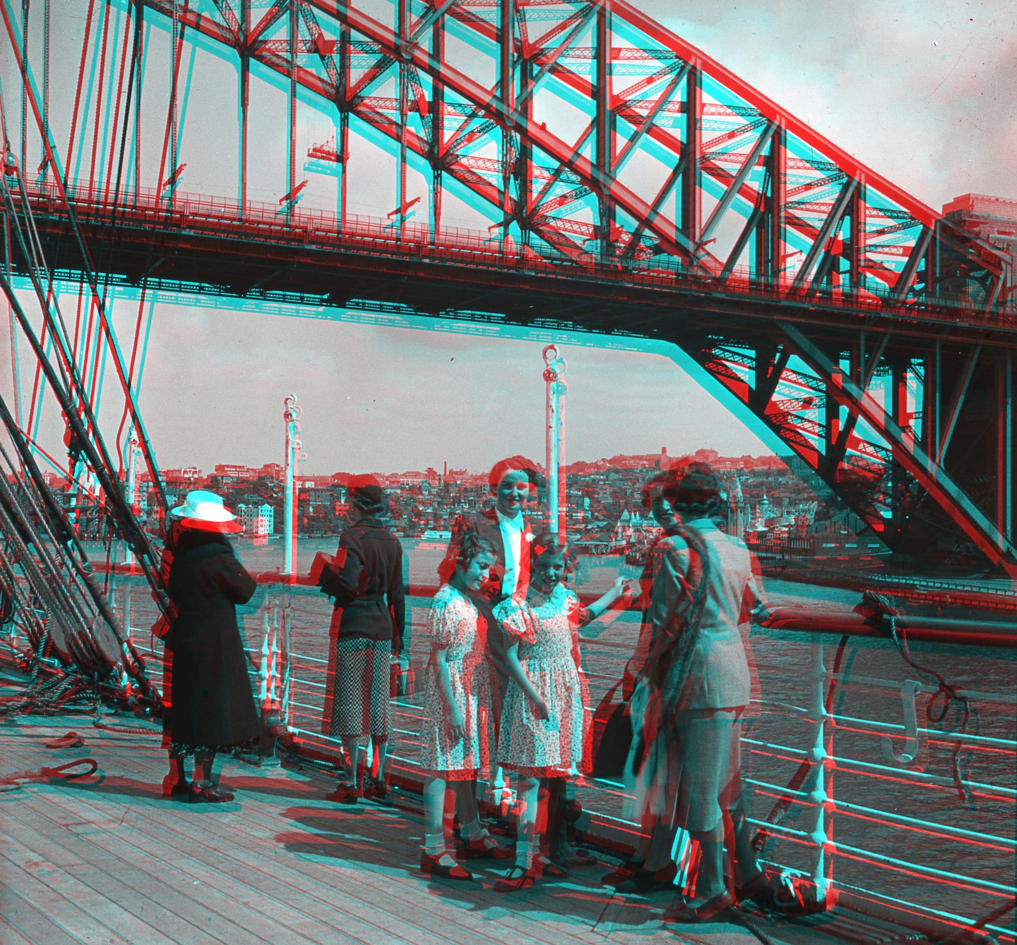 Richard Tandler Collection by Restore Conservation Services. Image copyright of Restore Conservation Services. Edited vintage shot of two young girls an older women standing in front of the Sydney Harbour Bridge. Original image in black and white with added blue and red overlay. 