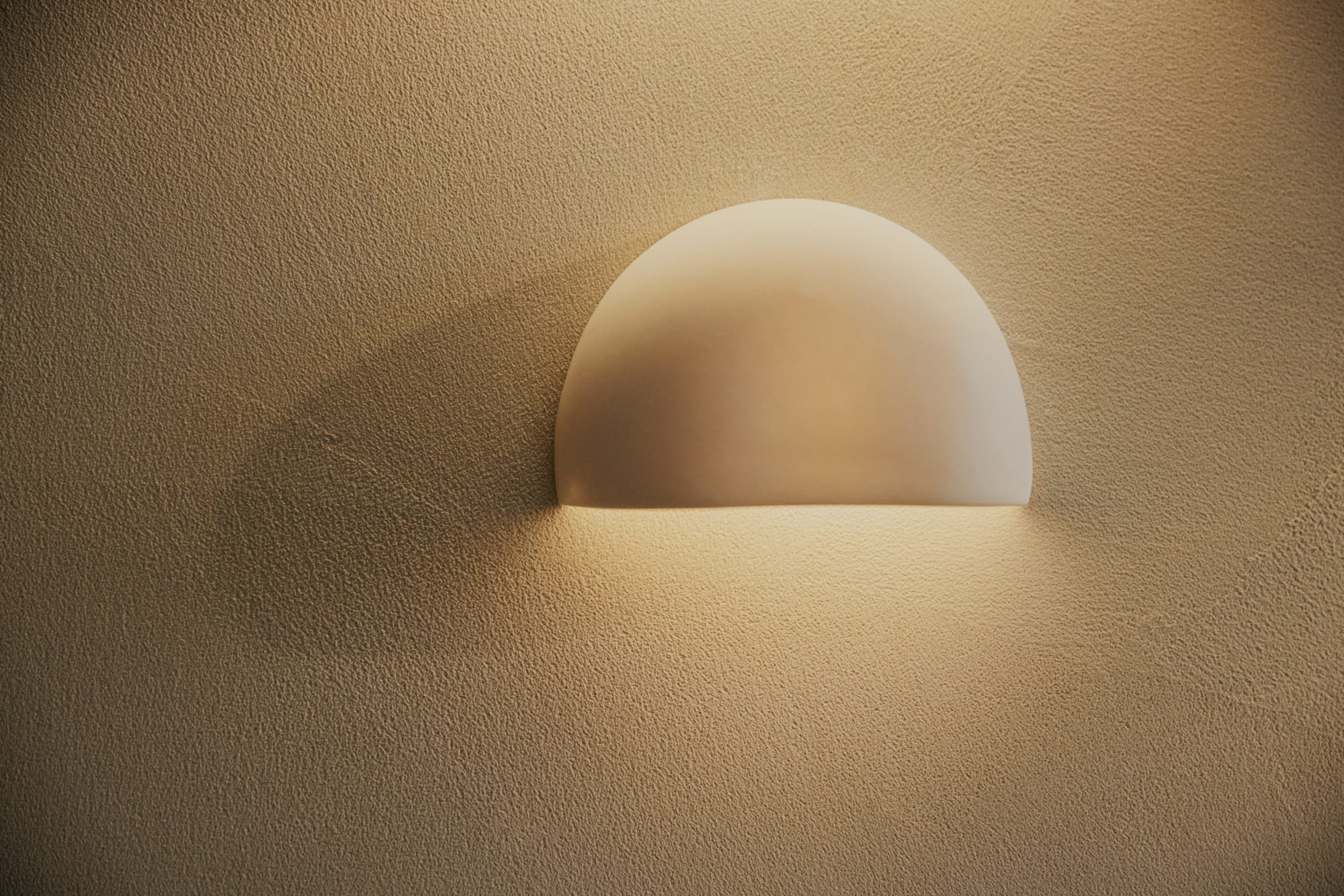 Crescent Wall Sconce by Studio Enti on a white rendered wall.