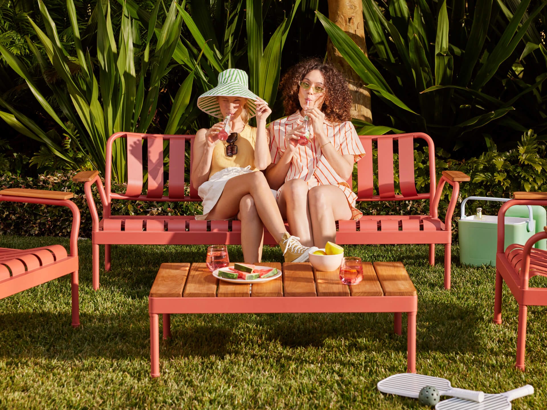 Torakina Outdoor Lounge Set by Koala in Outback Rose. Pink metal lounge bench and wooden coffee table in green backyard garden. 