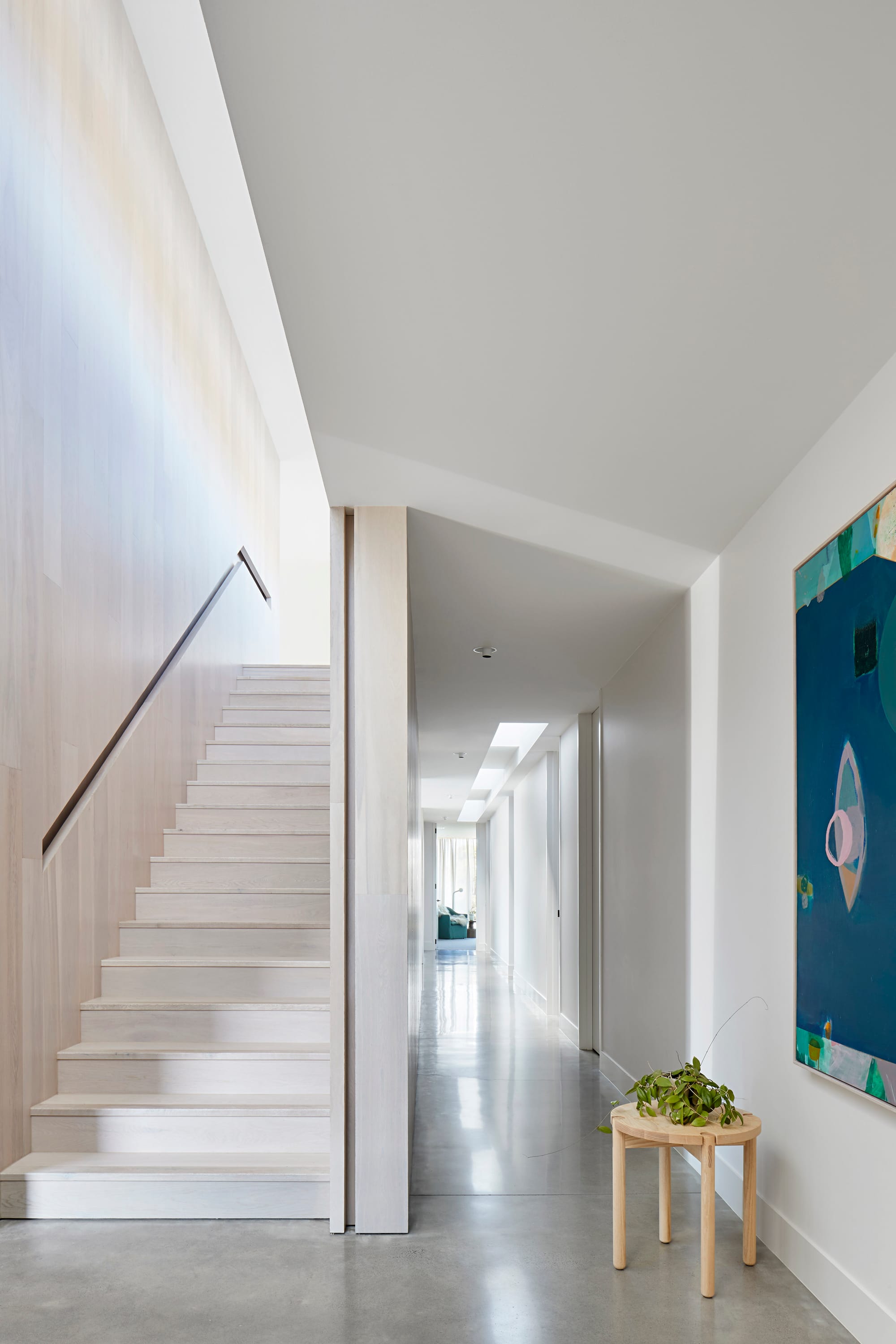 Wildcoast Road by Rachcoff Vella Architecture. Photography by Shannon McGrath. Interior hallway with white staircase and polished concrete flooring in coastal residential home. 