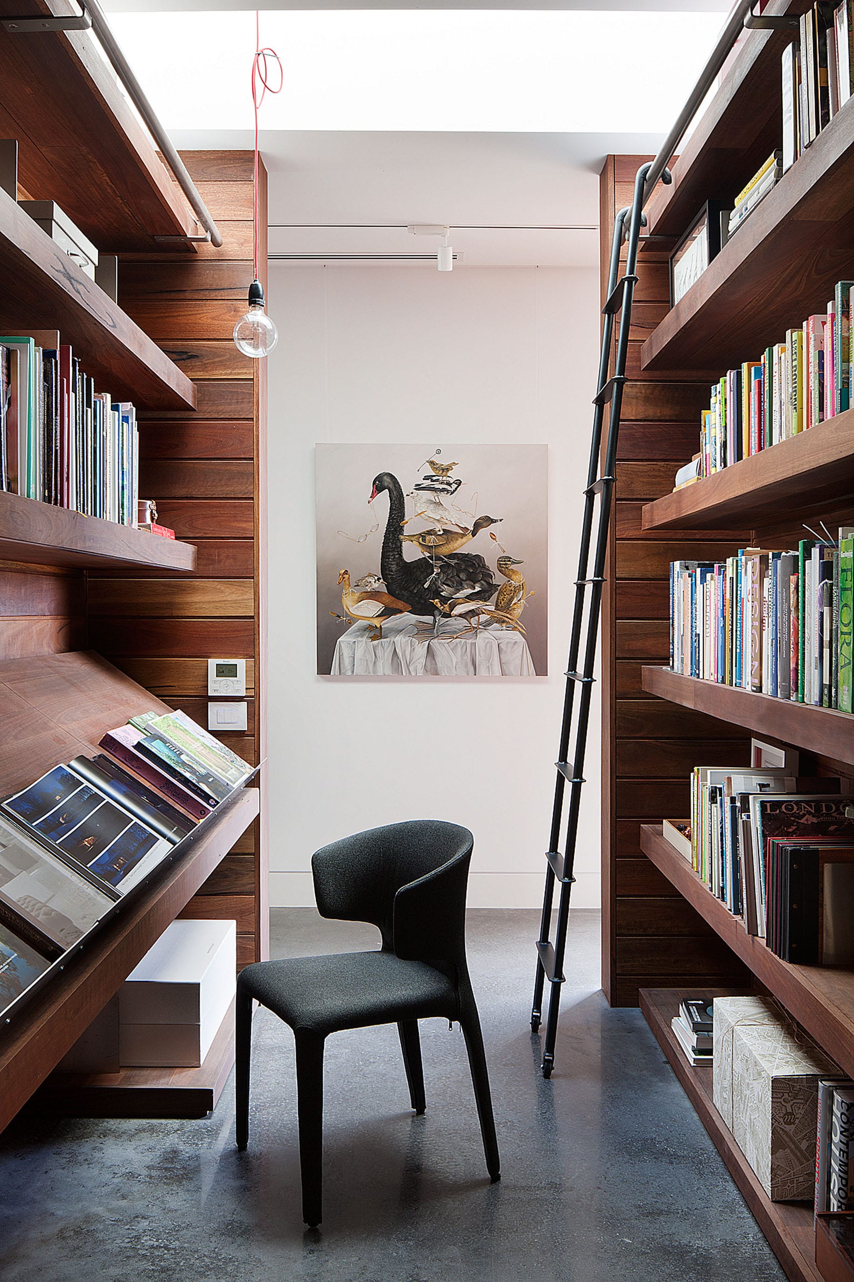 Piermont Jacksons Road by Rachcoff Vella Architecture. Photography by Lean Timms. Residential library shelving made of warm timer with black polished concrete flooring 