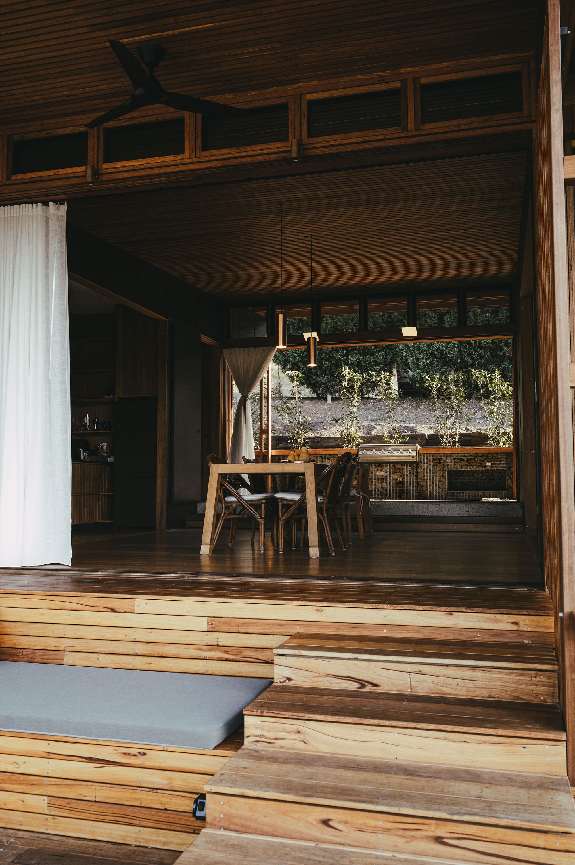 The Summer House at Little Valley Farm. Photography by Milou Hofman Photography. Indoor/outdoor dining area with timber steps leading from outside to timber floors inside.