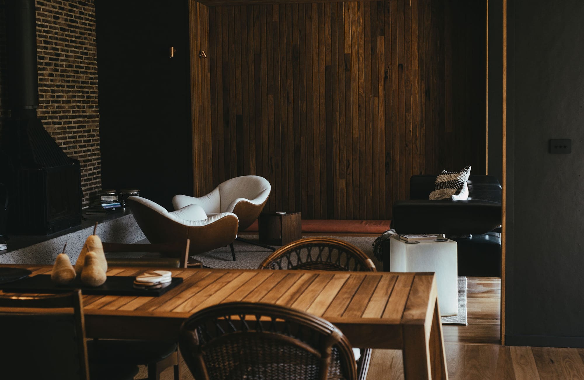 The Summer House at Little Valley Farm. Photography by Milou Hofman Photography. Open plan living and dining area with timber and brick walls, mismatched mid-century modern furniture and grey carpet.