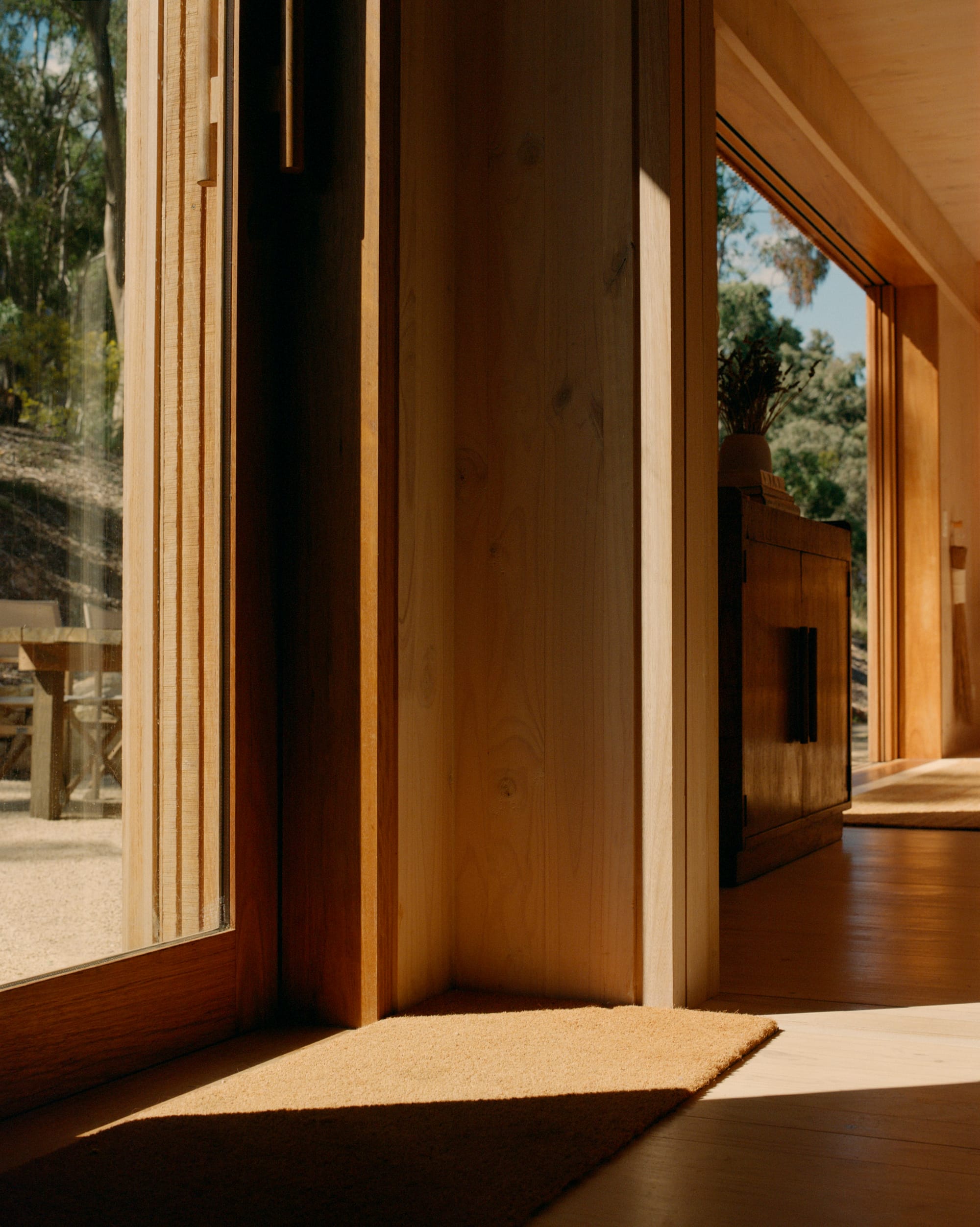 Practice Ground. Photography by Saskia Wilson. Low angle close up shot of timber joinery on sliding timber and glass door frame, opening from residential interior to gravel courtyard.