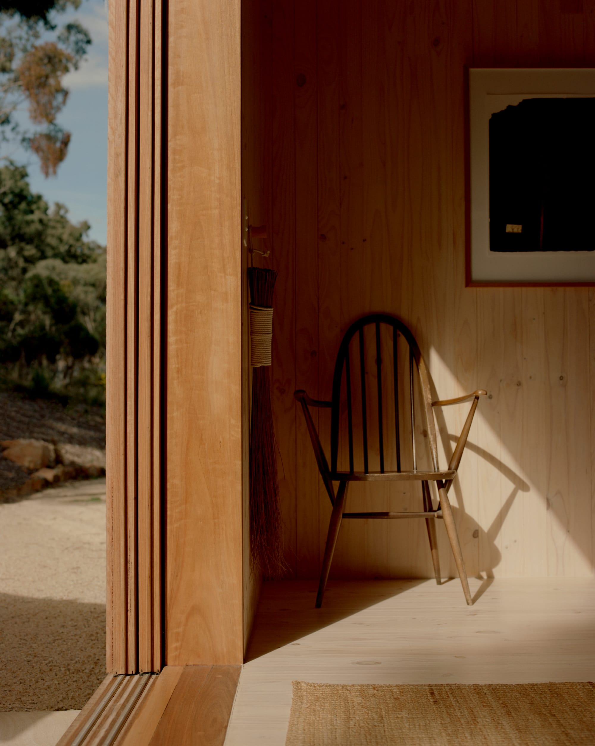 Practice Ground. Photography by Saskia Wilson. Interior space finished with timber and detail of sliding door track, with outside courtyard visible to the left.