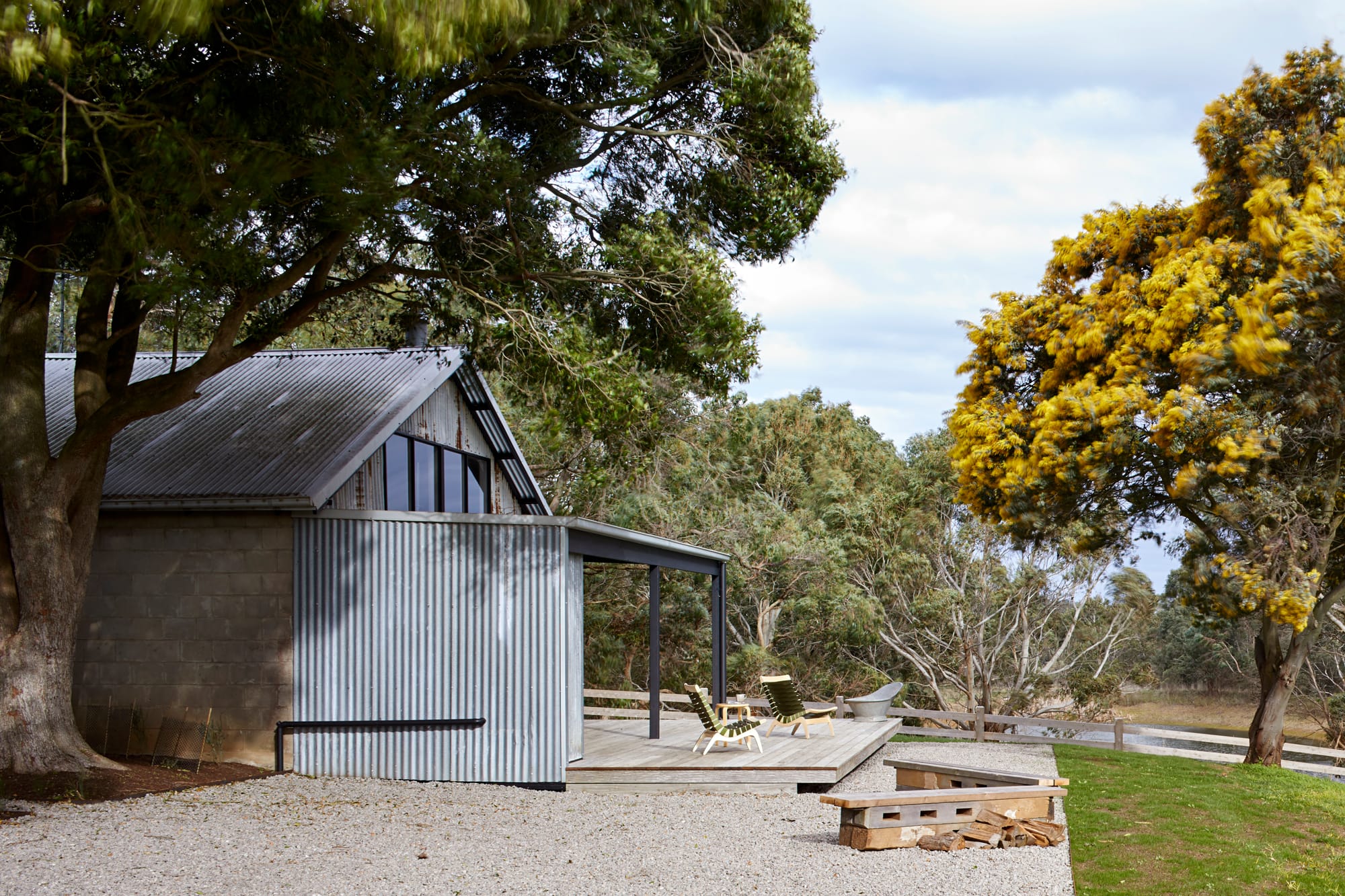 Firewood and Candles by Rachcoff Vella Architecture. Photography by Tatjana Plitt. Outdoor deck with metal walls and gravel floors in rural setting. 