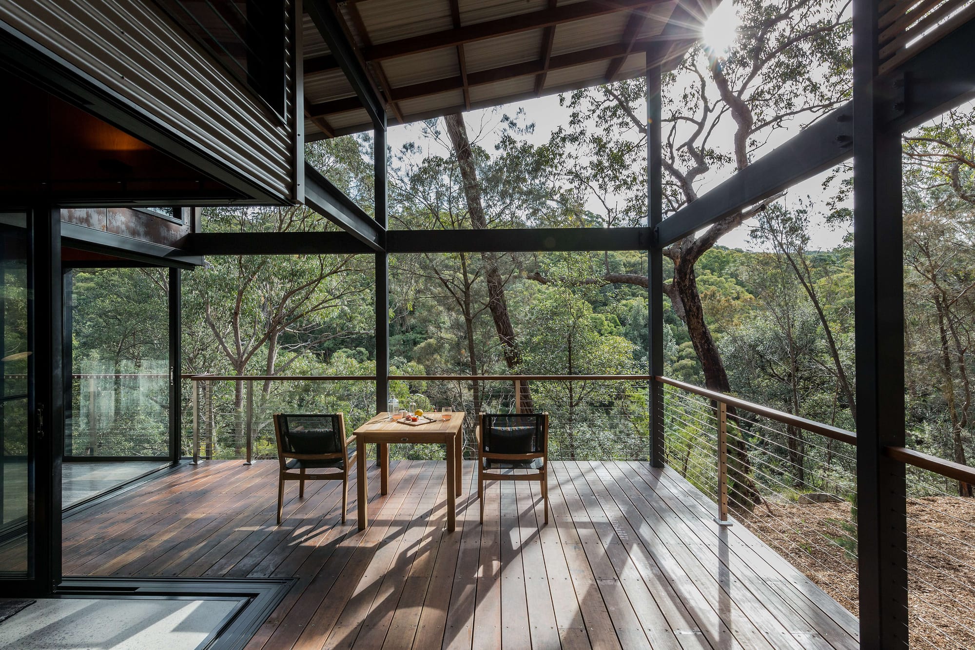 Spicers Sangoma by Barbara Tarnawski Architects. Timber deck with table and chairs overlooking hilly bushland and native plantlife. 