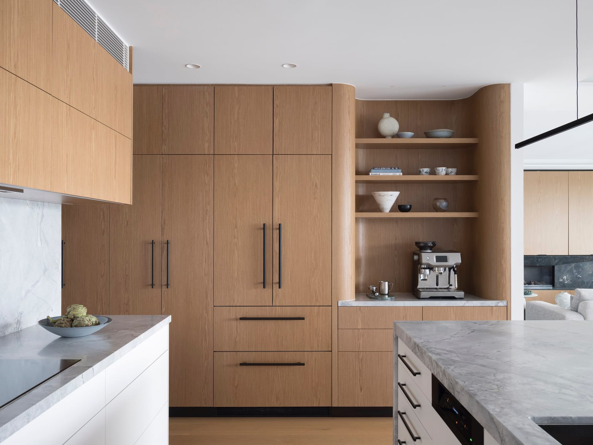 Sailors Bay by Castlepeake Architects. Photography by Tom Ferguson. Timber kitchen cabinetry with curved finishes, floating shelves, black detailing and marble benchtops and splash backs.