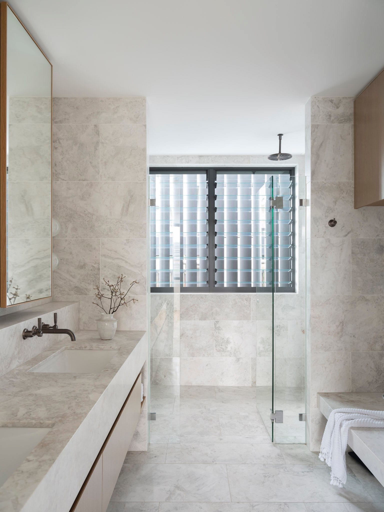 Sailors Bay by Castlepeake Architects. Photography by Tom Ferguson. Bathroom with light marbled tiles on floors, walls, splash backs and countertops, with glass wet room shower at end. 