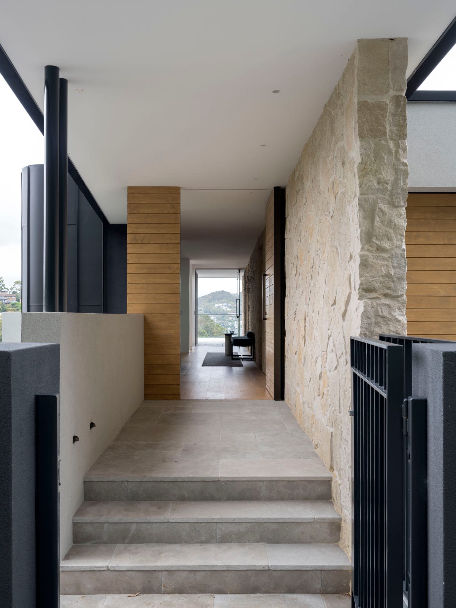 Entry to house with the door open showing the harbour views through the house and a sandstone wall to the right.