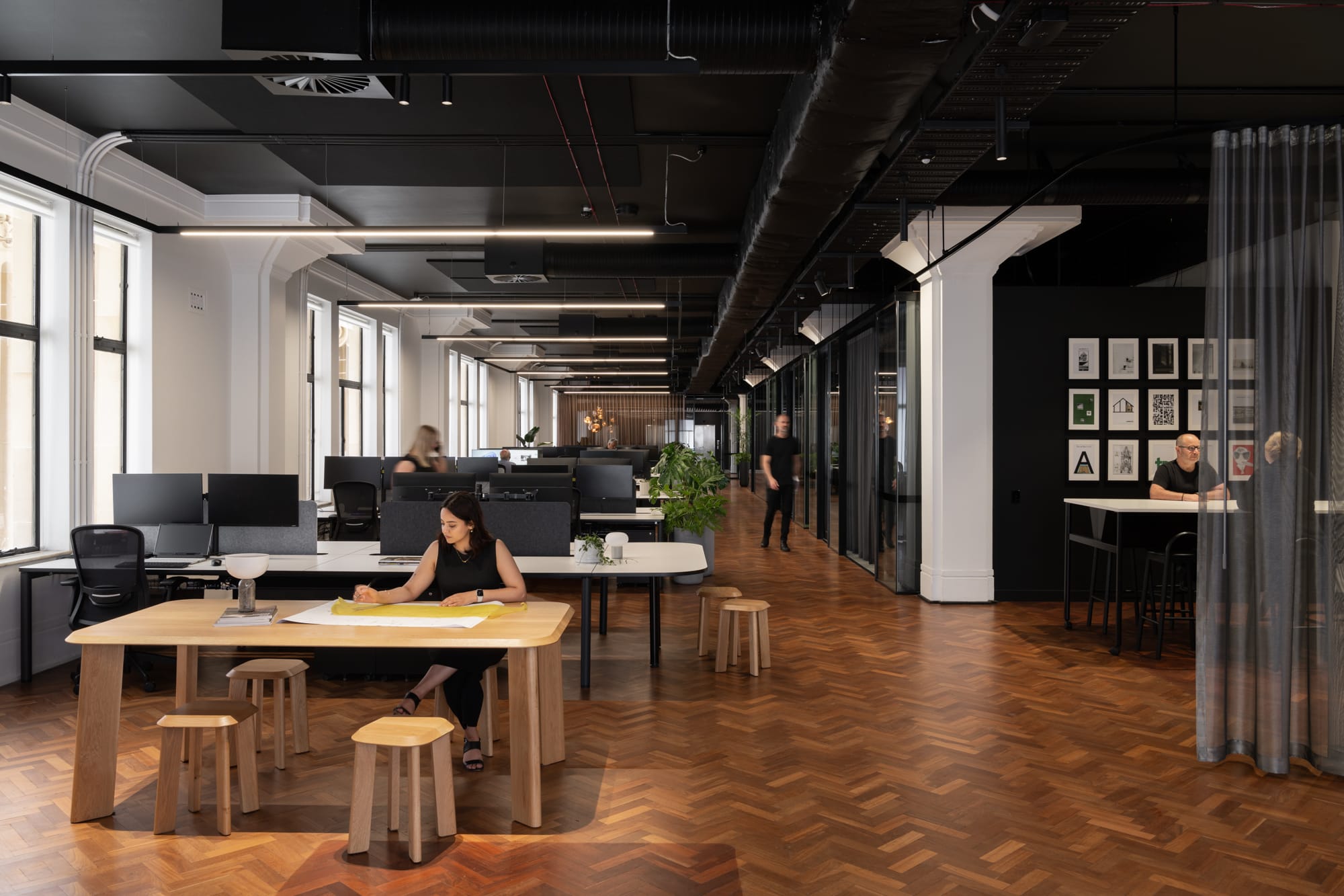 Hunt Architects Perth Studio. Photography by Dion Robeson. Office space with herringbone flooring, black ceiling, sheer curtains, and a mix of white and timber desks. 