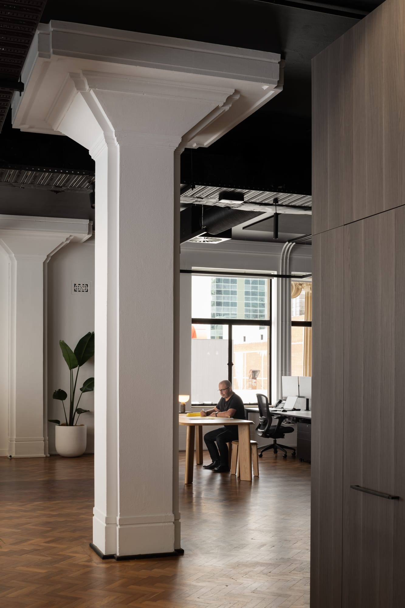 Hunt Architects Perth Studio. Photography by Dion Robeson. Large heritage white column inside office space, with herringbone flooring and large windows. 