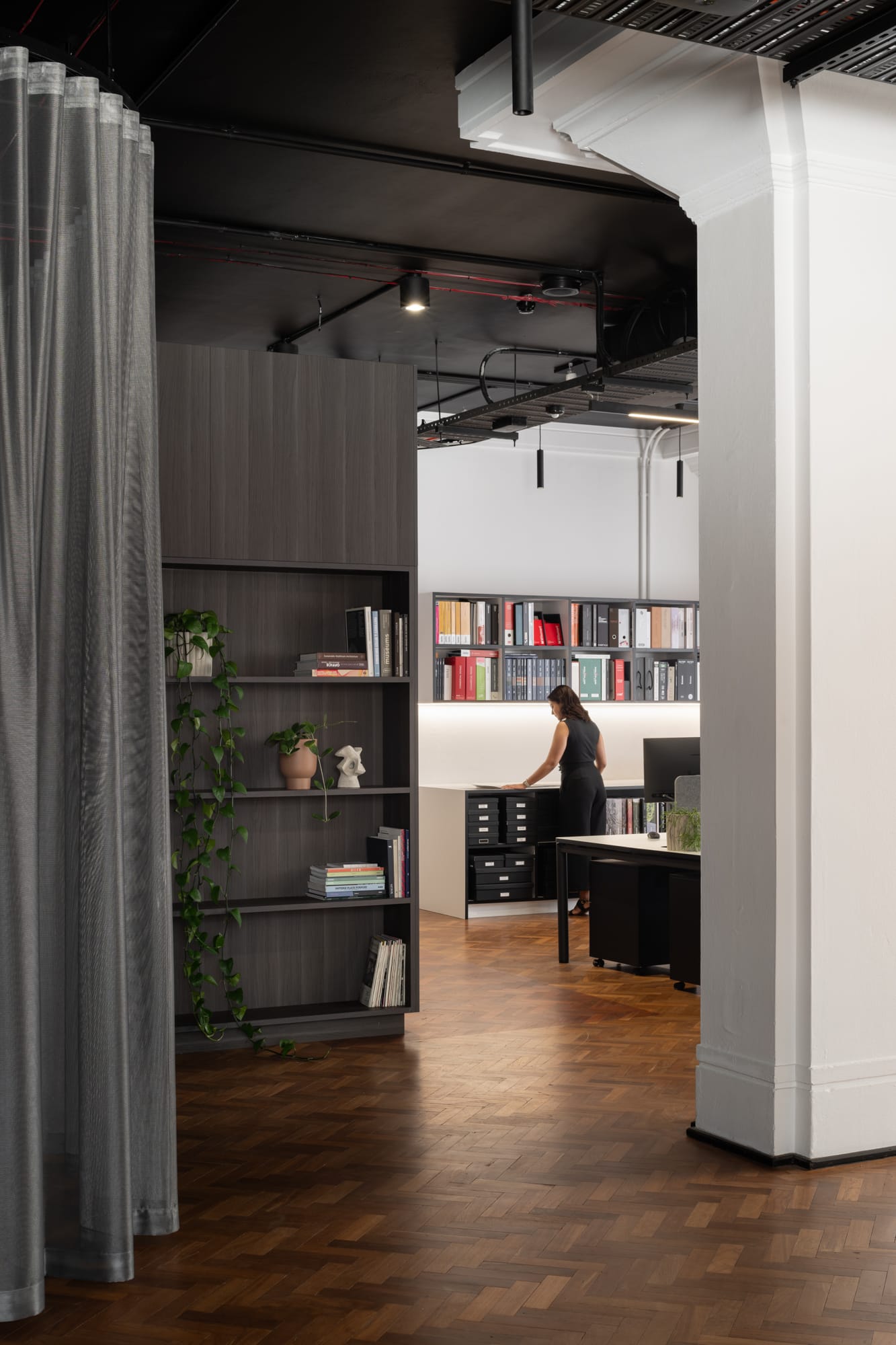 Hunt Architects Perth Studio. Photography by Dion Robeson. Office space with large white heritage columns, herringbone flooring, dark timber joinery and grey sheer curtains.