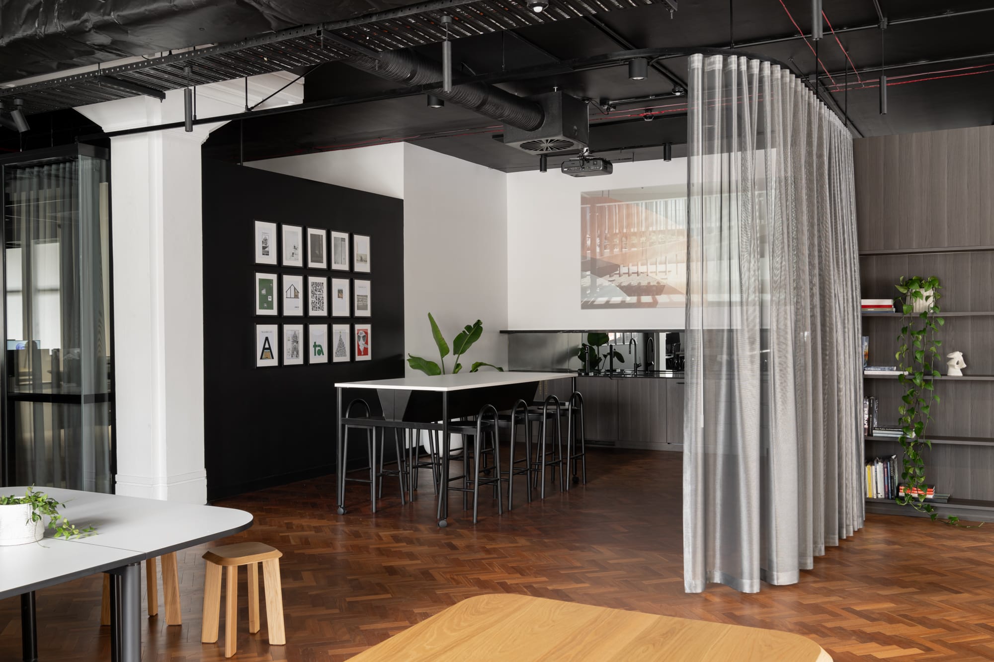 Hunt Architects Perth Studio. Photography by Dion Robeson. Staff area with herringbone timber floors, sheer curtain dividers and tall white table. 