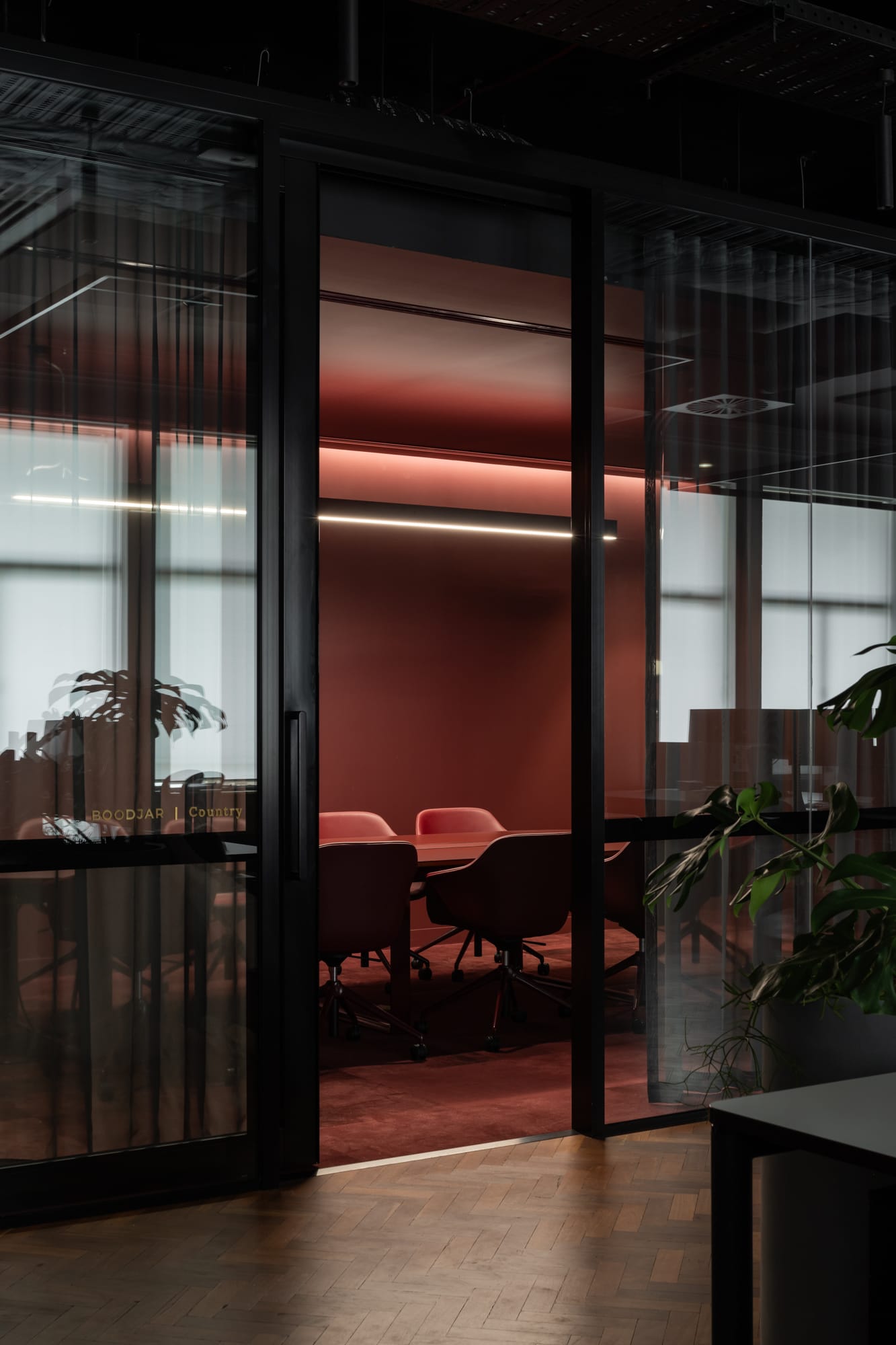 Hunt Architects Perth Studio. Photography by Dion Robeson. Office space with red flooring, walls and furniture, with black framed glass walls and door. 