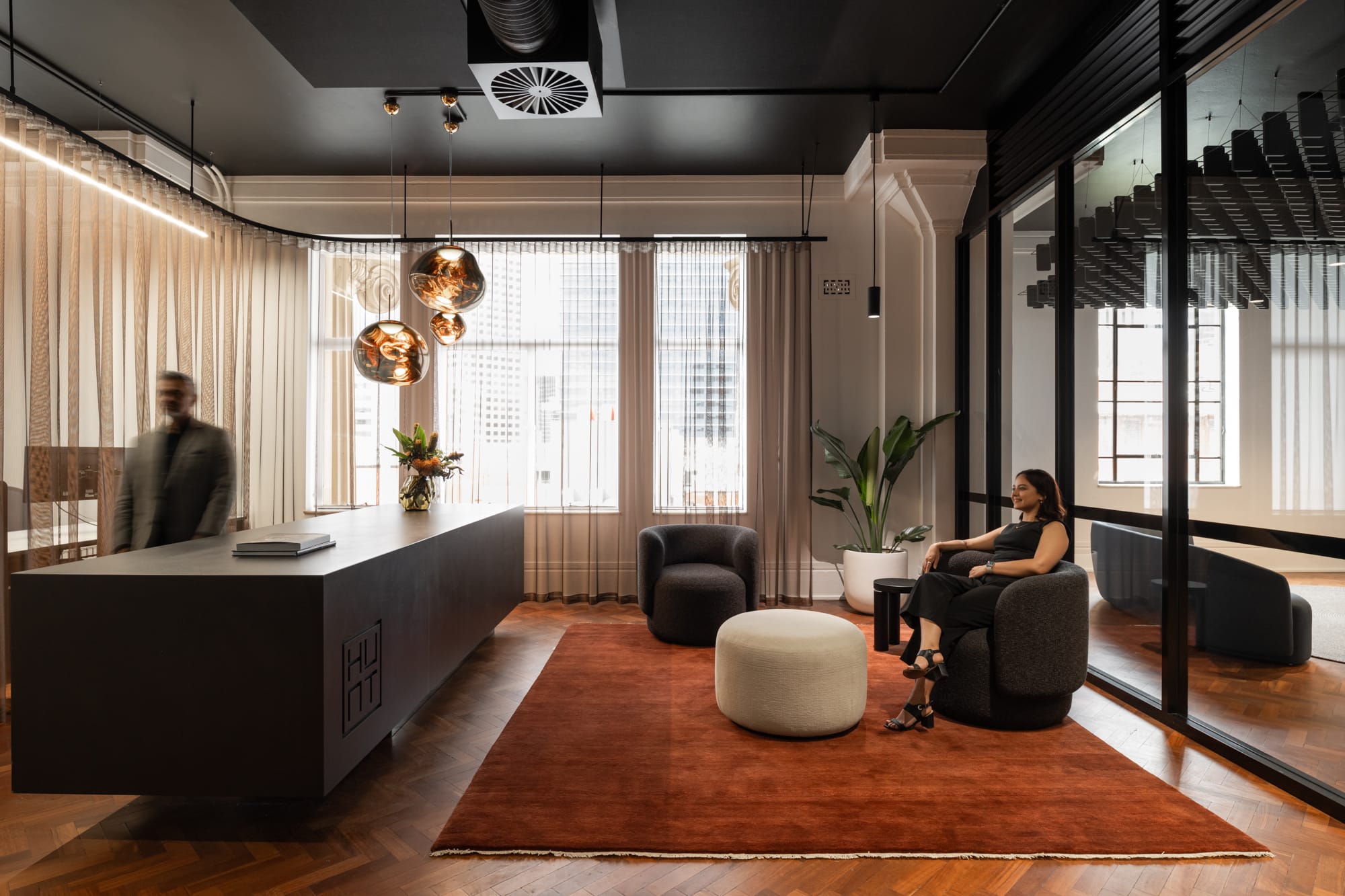 Hunt Architects Perth Studio. Photography by Dion Robeson. Reception seating area with large, dark desk, burnt orange carpet, timber floors and black ceilings. 