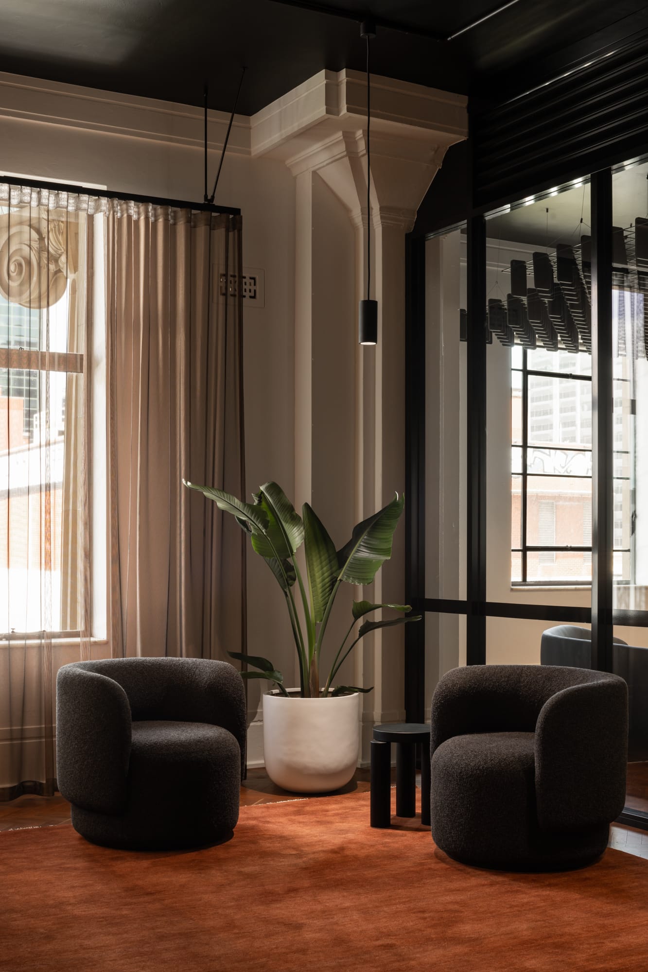 An interior shot of the Hunt Architects Perth Studio showing the seating area in the lobby with two occasional chairs and a terracotta coloured rug.