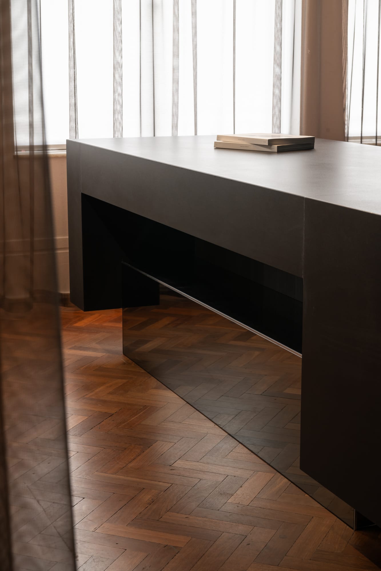 Hunt Architects Perth Studio. Photography by Dion Robeson. Close up of dark reception desk with matte and gloss combined finish, on herringbone flooring.